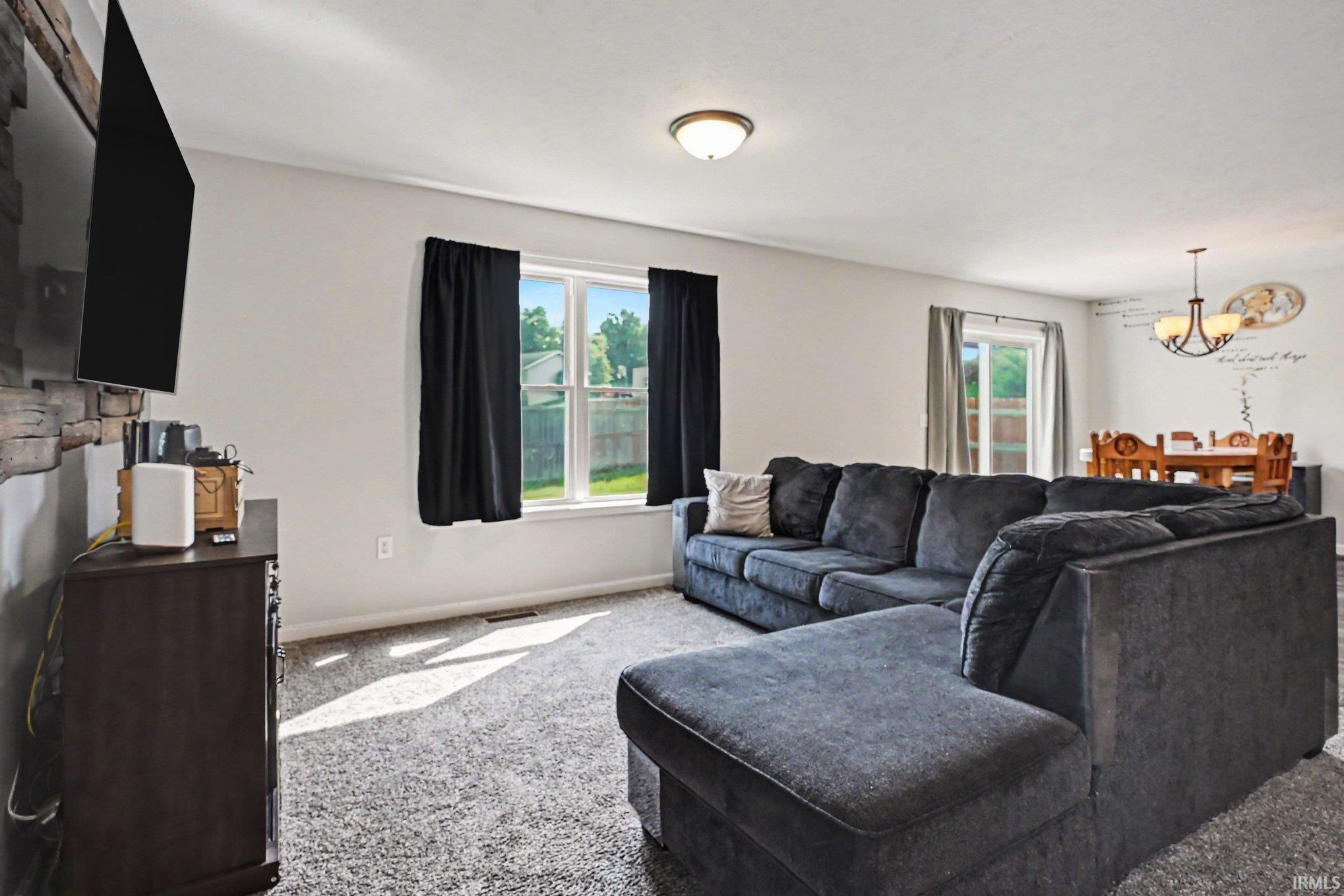 Carpeted living area featuring a stone-accented wall, white trim, and multiple windows