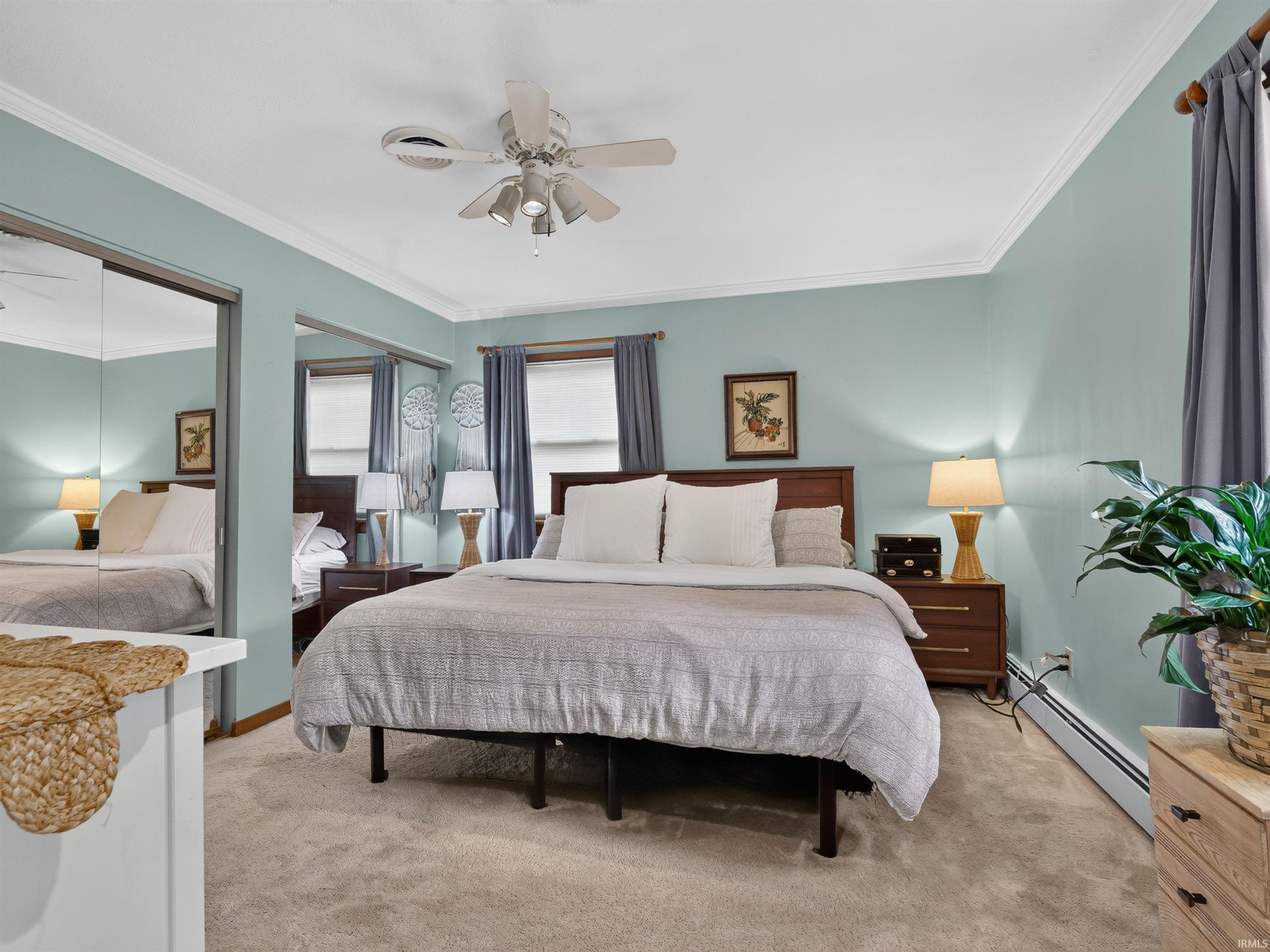 Bedroom featuring light blue walls, crown molding, and carpeted flooring