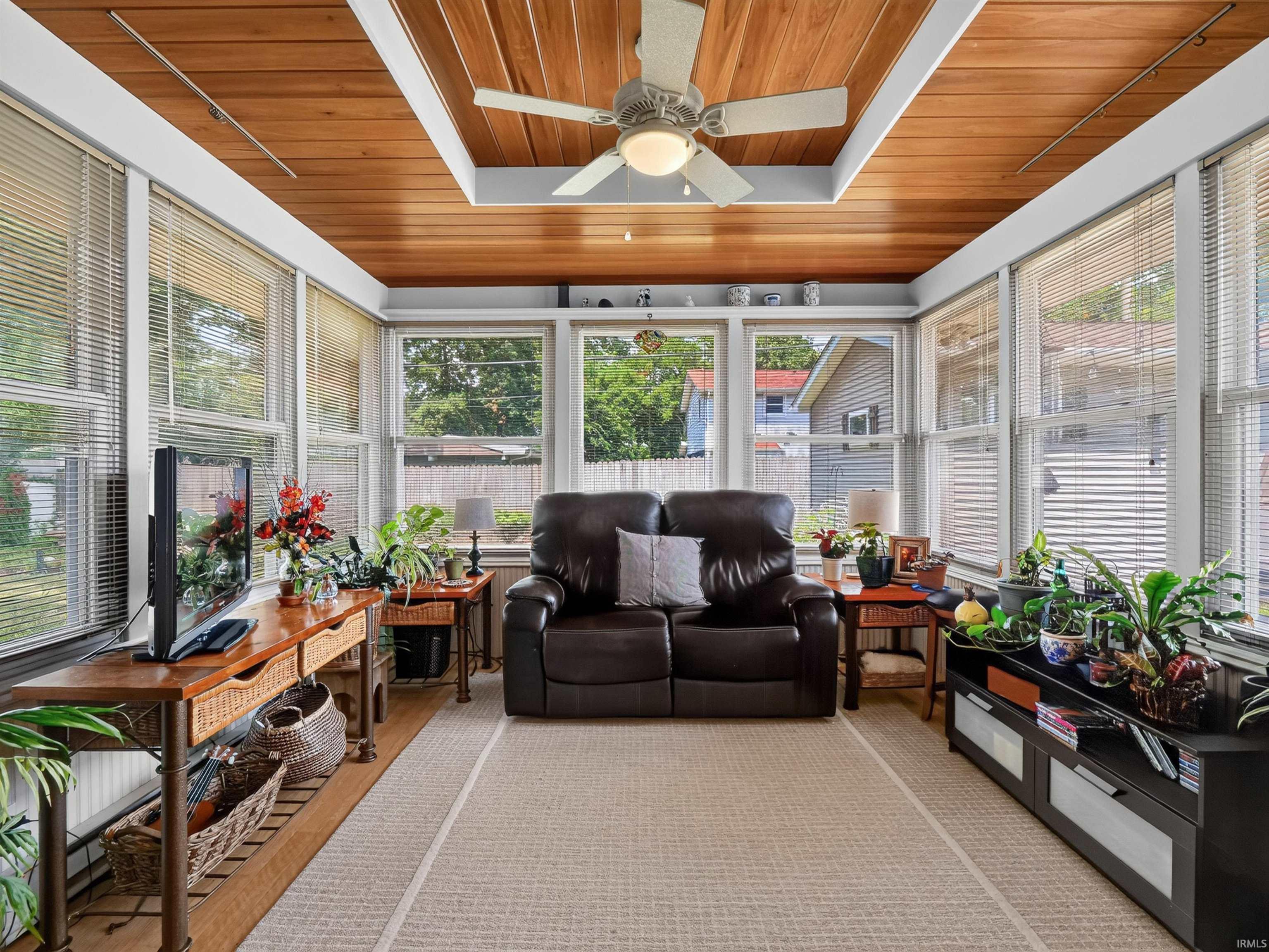 Four season room featuring a wood-panel ceiling with a ceiling fan, numerous windows with blinds, light-toned flooring, and a window framing the outdoors