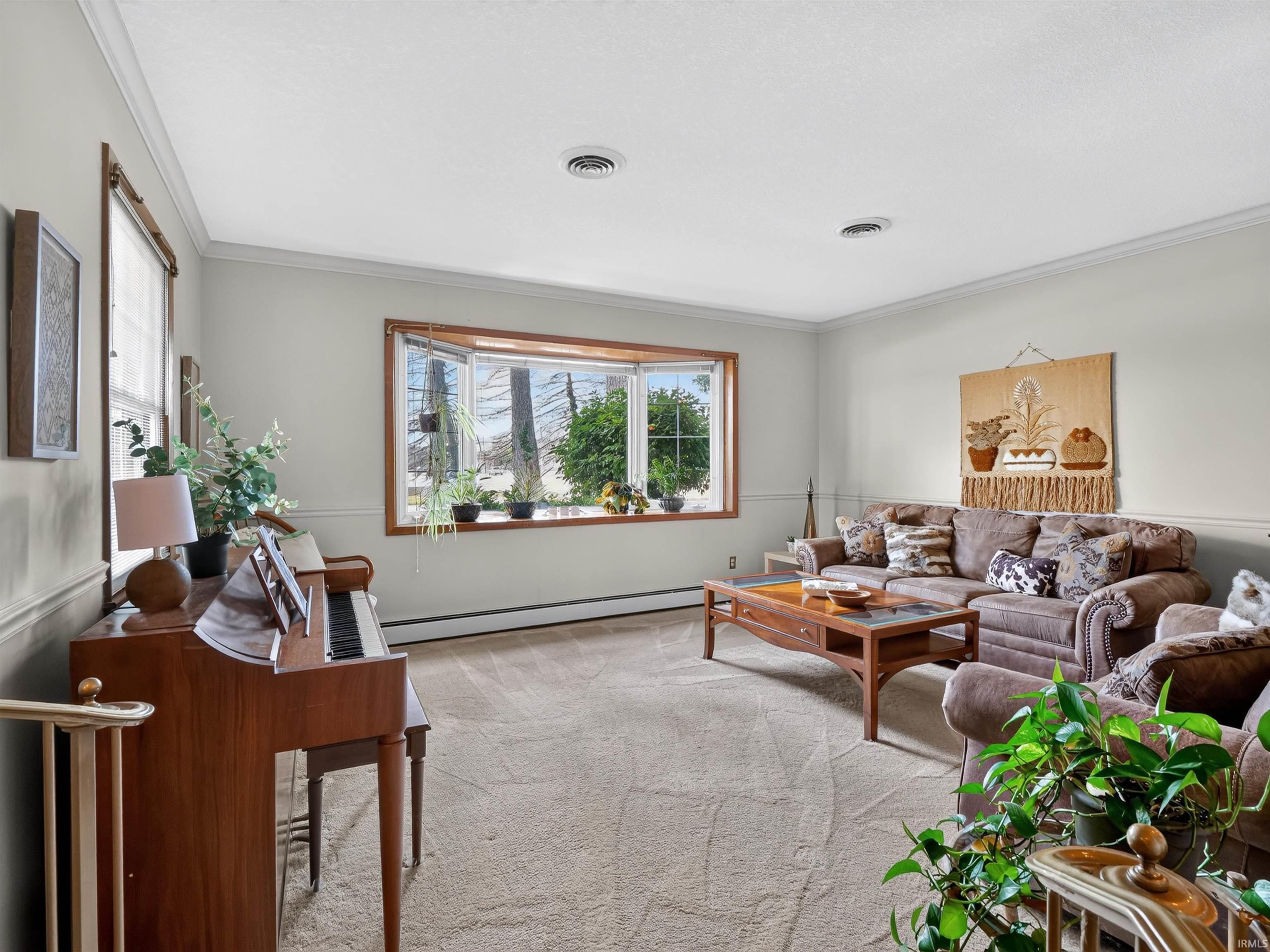 Living room featuring a large bay window with wood trim, neutral carpeting, and recessed lighting