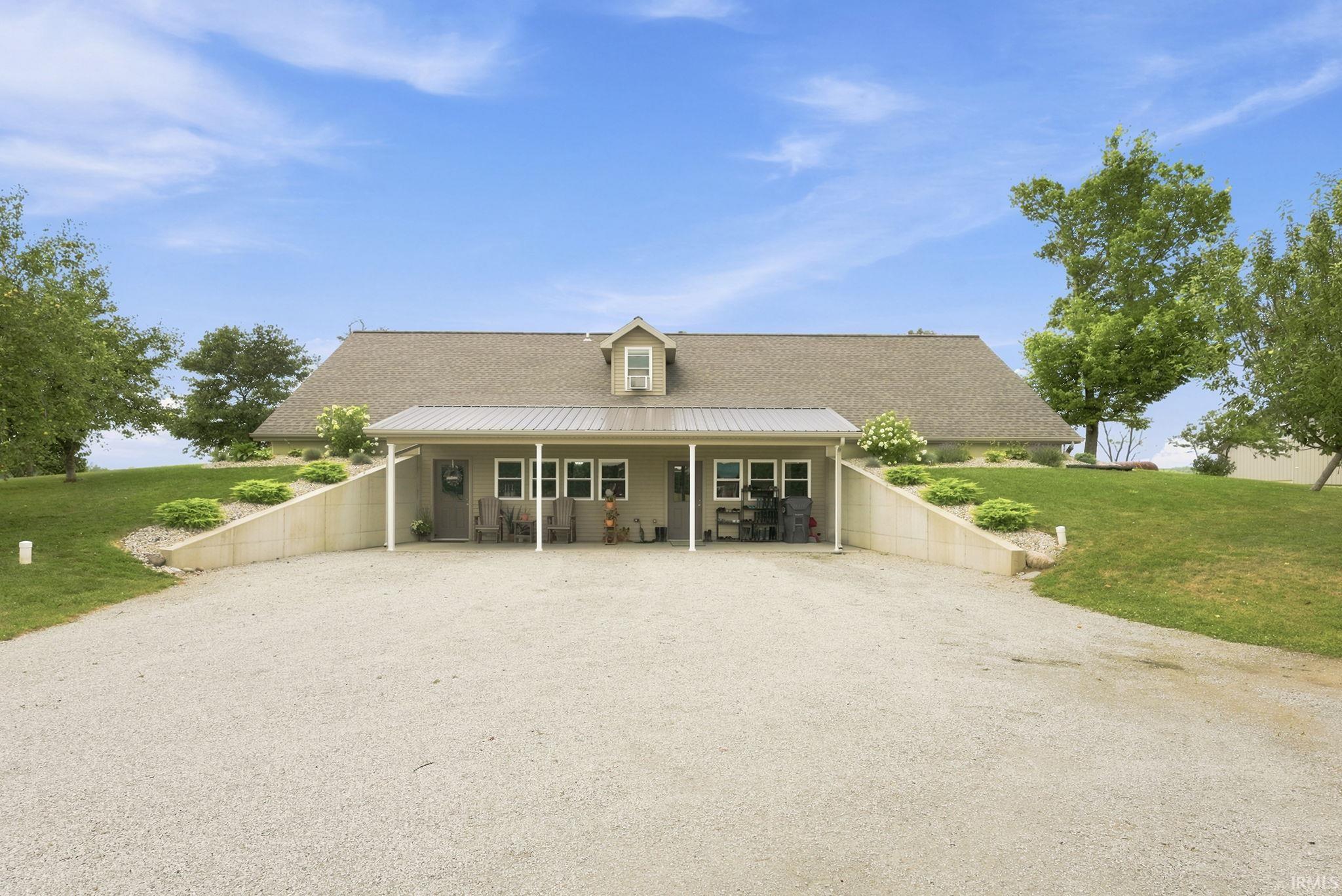 Single-story residence featuring a covered entry porch with white support columns, a dormer window, and a gravel driveway