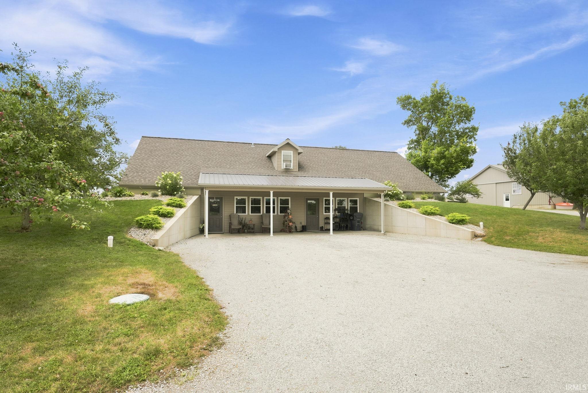 Ranch-style residence featuring a gravel driveway, covered patio, and dormer window
