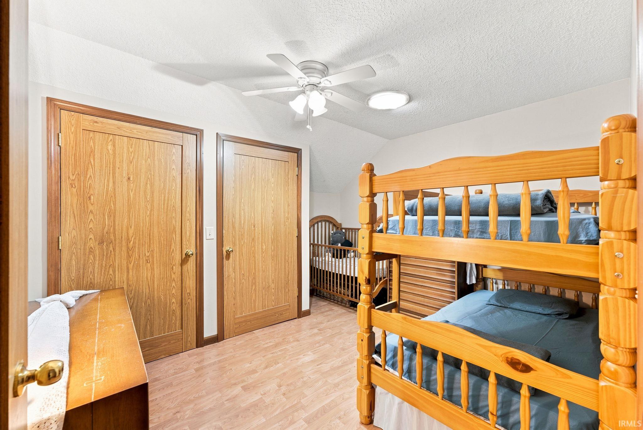 Room featuring wood-finish flooring, two wood paneled doors, and a ceiling fan with integrated lighting
