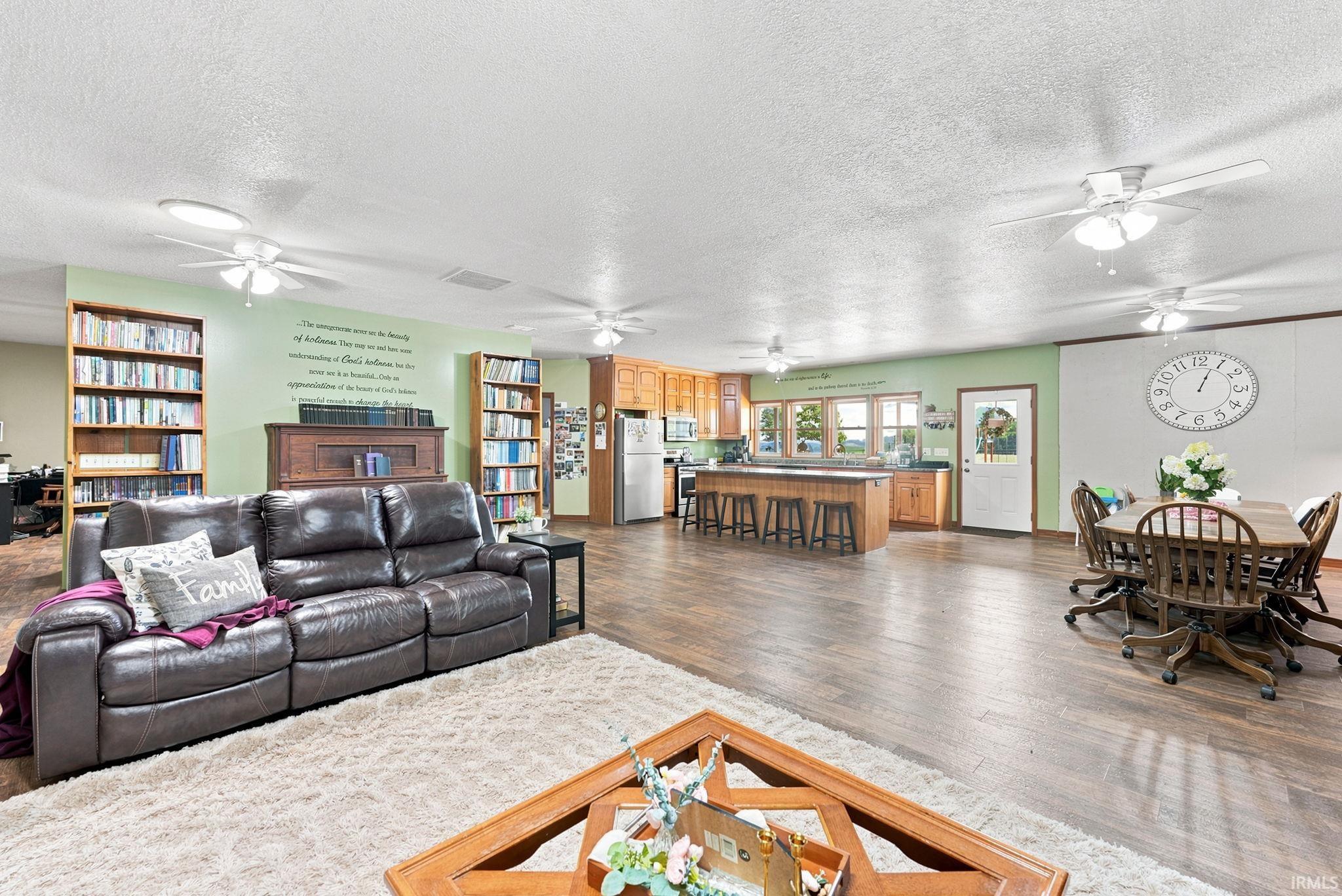 Spacious open-concept living area featuring wood-finish flooring, recessed lighting, and multiple ceiling fans