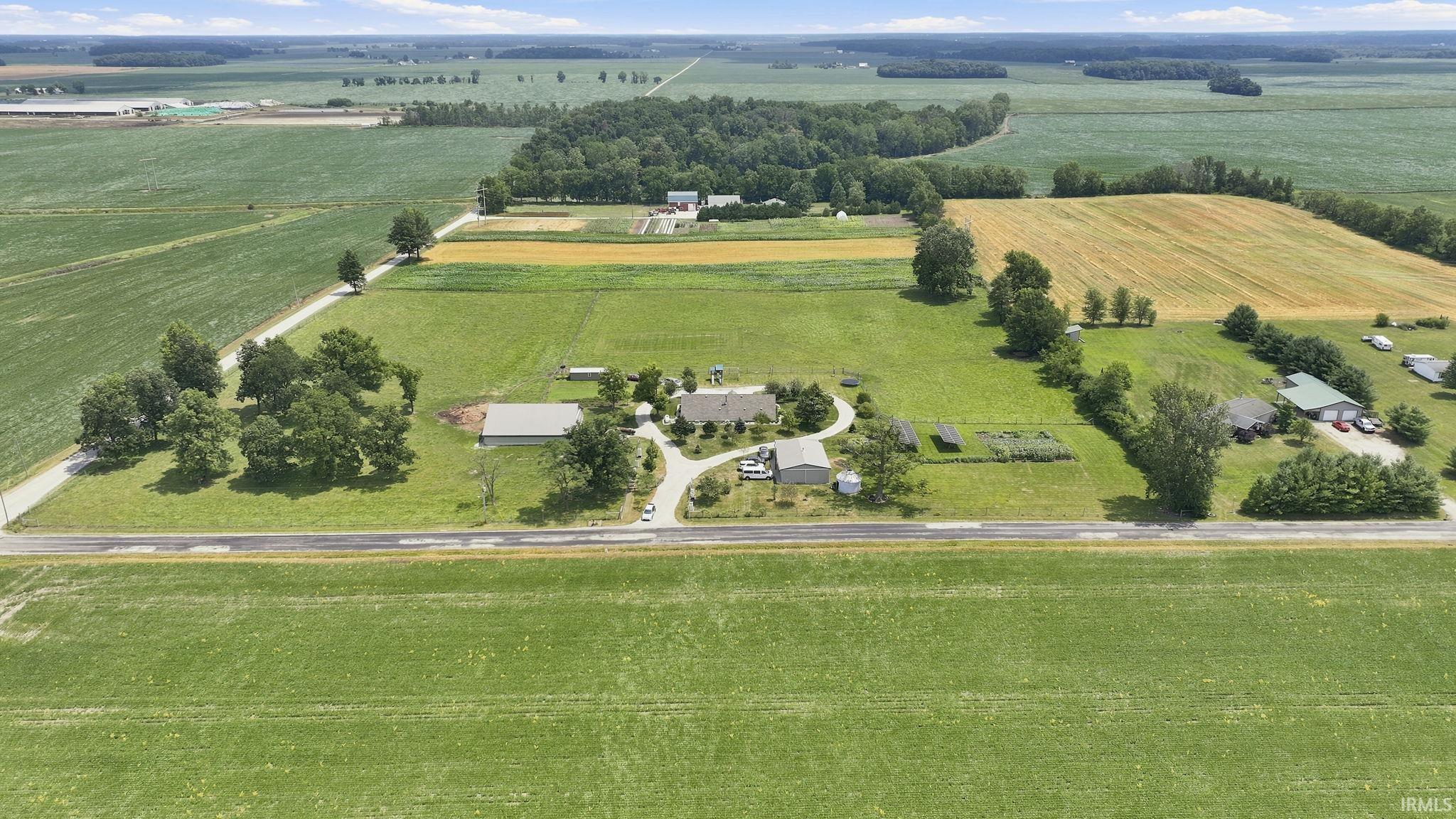 Expansive agricultural property featuring a primary residence with a circular driveway, multiple outbuildings, and cultivated fields