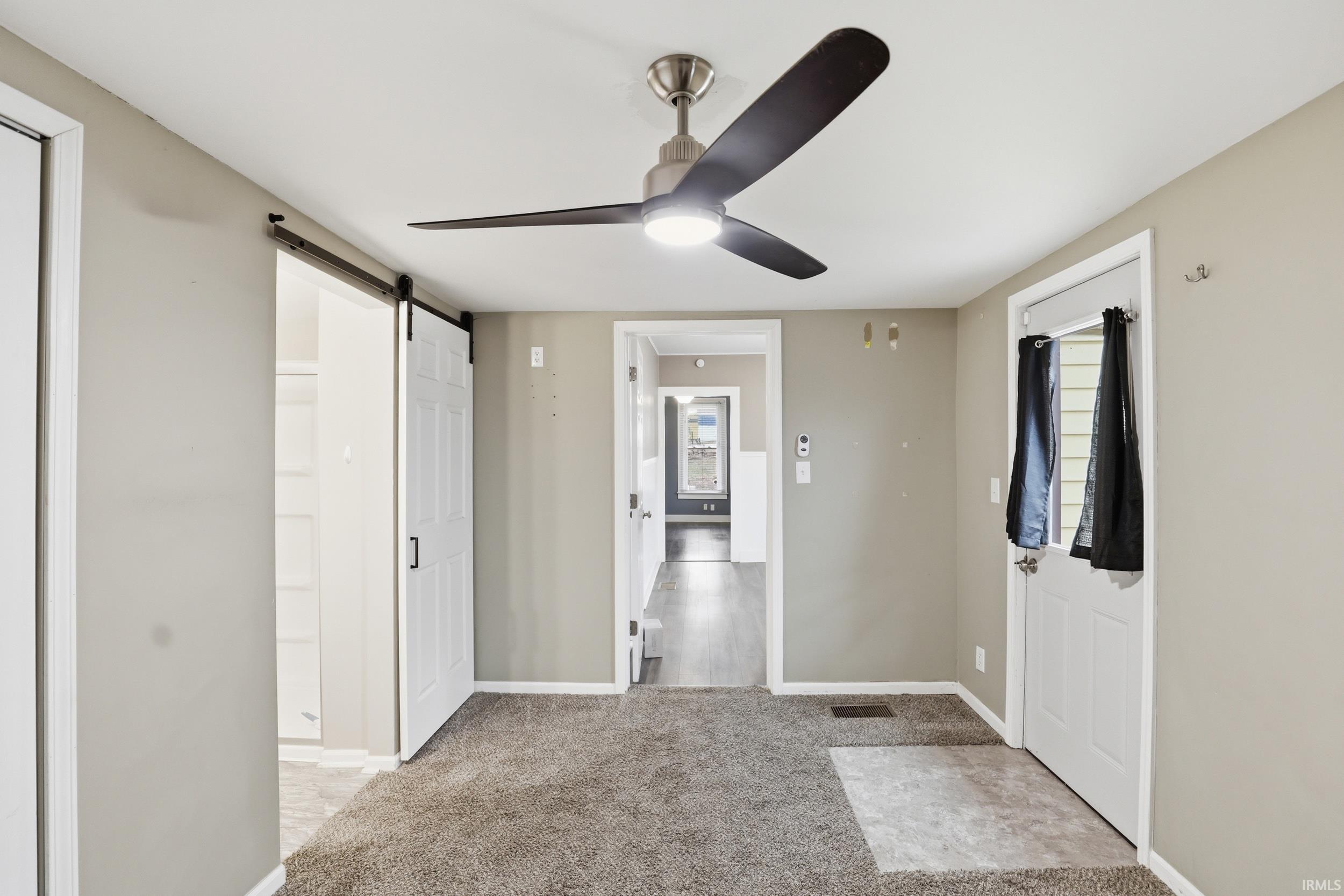 Foyer featuring a barn door, light carpet, and a ceiling fan