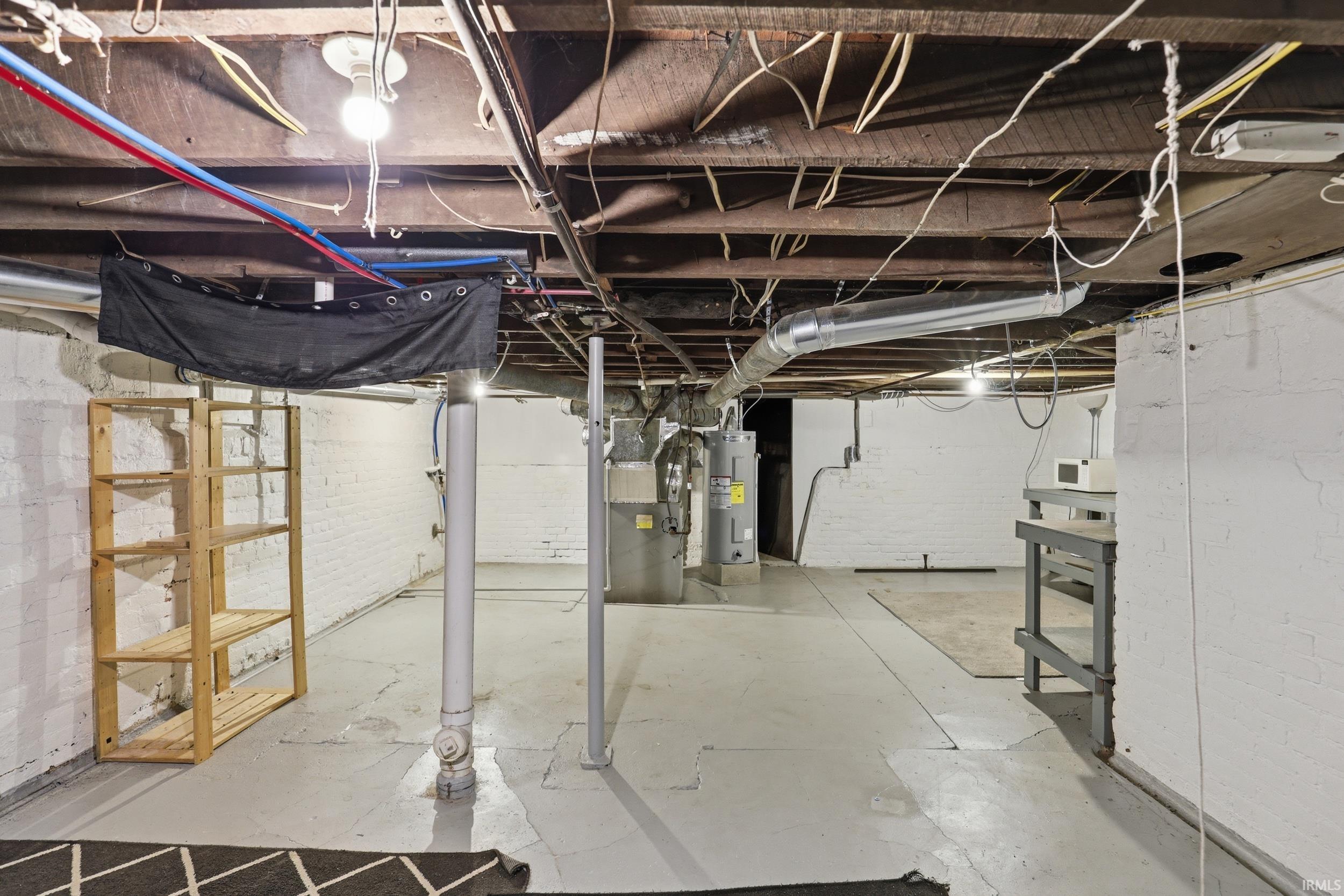 Unfinished below grade area featuring heating unit and water heater