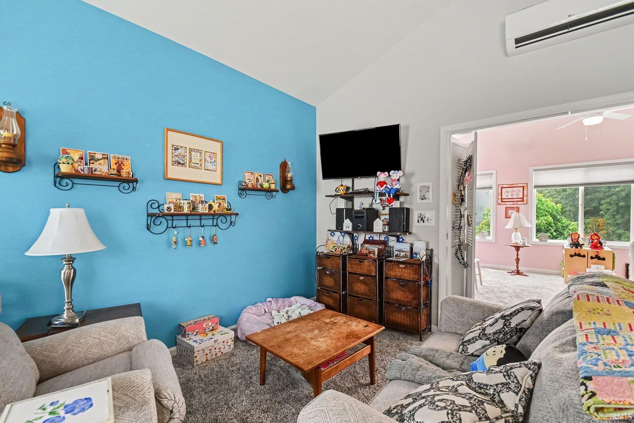 Living area featuring a vibrant accent wall, vaulted ceilings, and plush carpeting