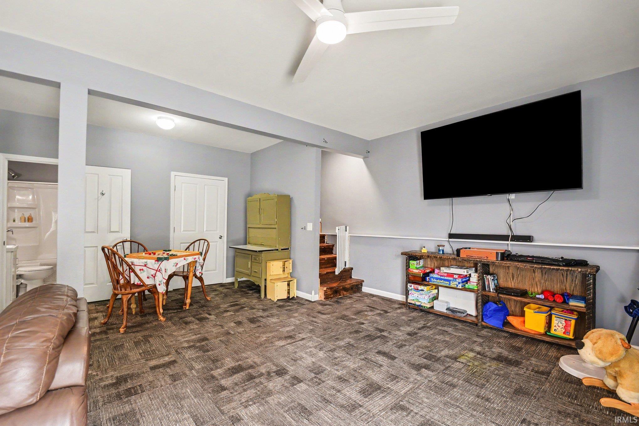 Spacious room featuring wood-finish flooring, light gray walls, and a ceiling fan