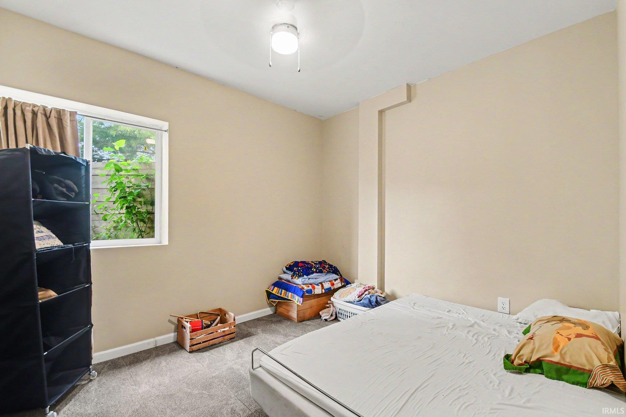 Carpeted room with a ceiling-mounted light fixture, neutral wall paint, and a white-framed window