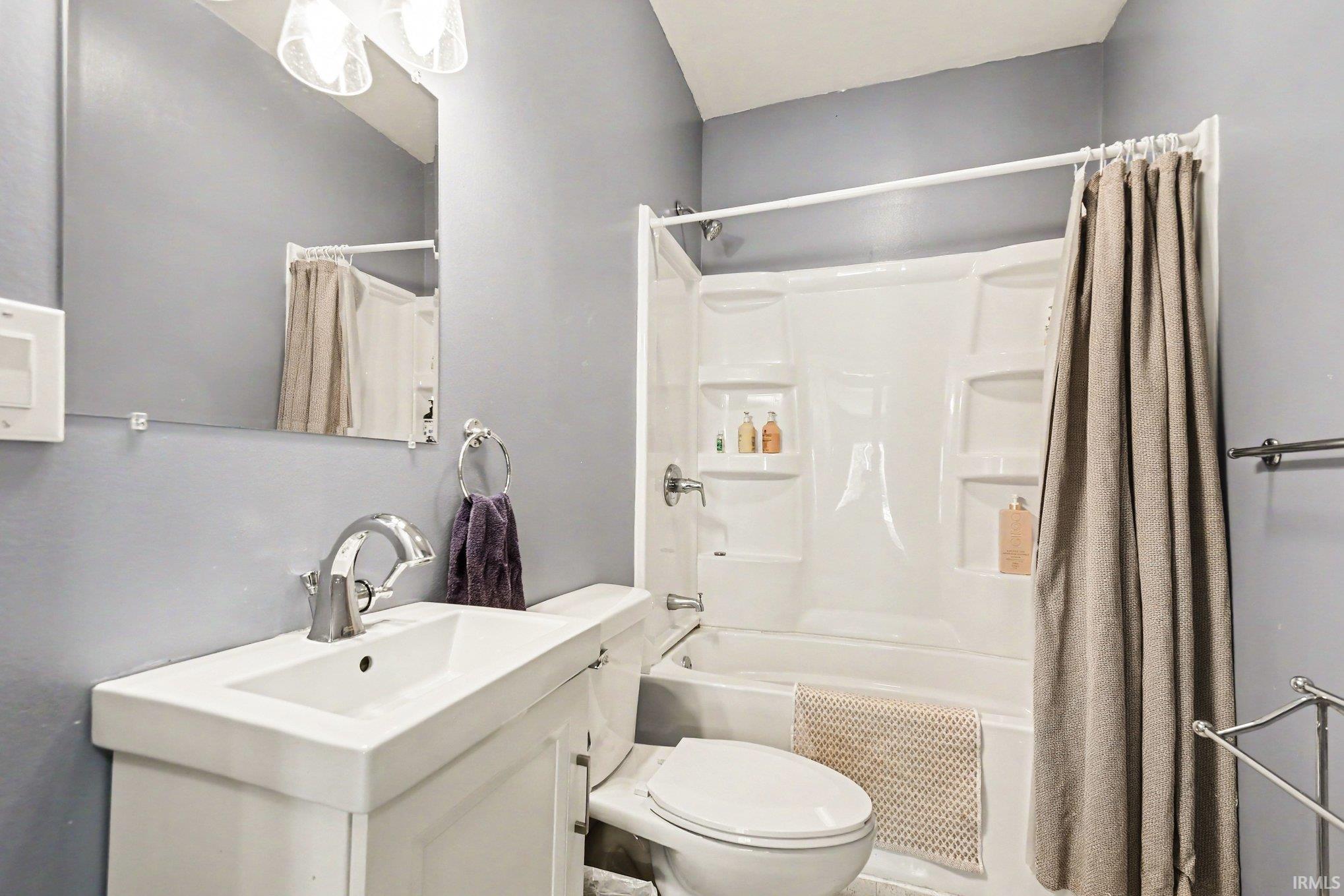 Bathroom featuring a single vanity with a white sink, chrome faucet, and mirrored medicine cabinet