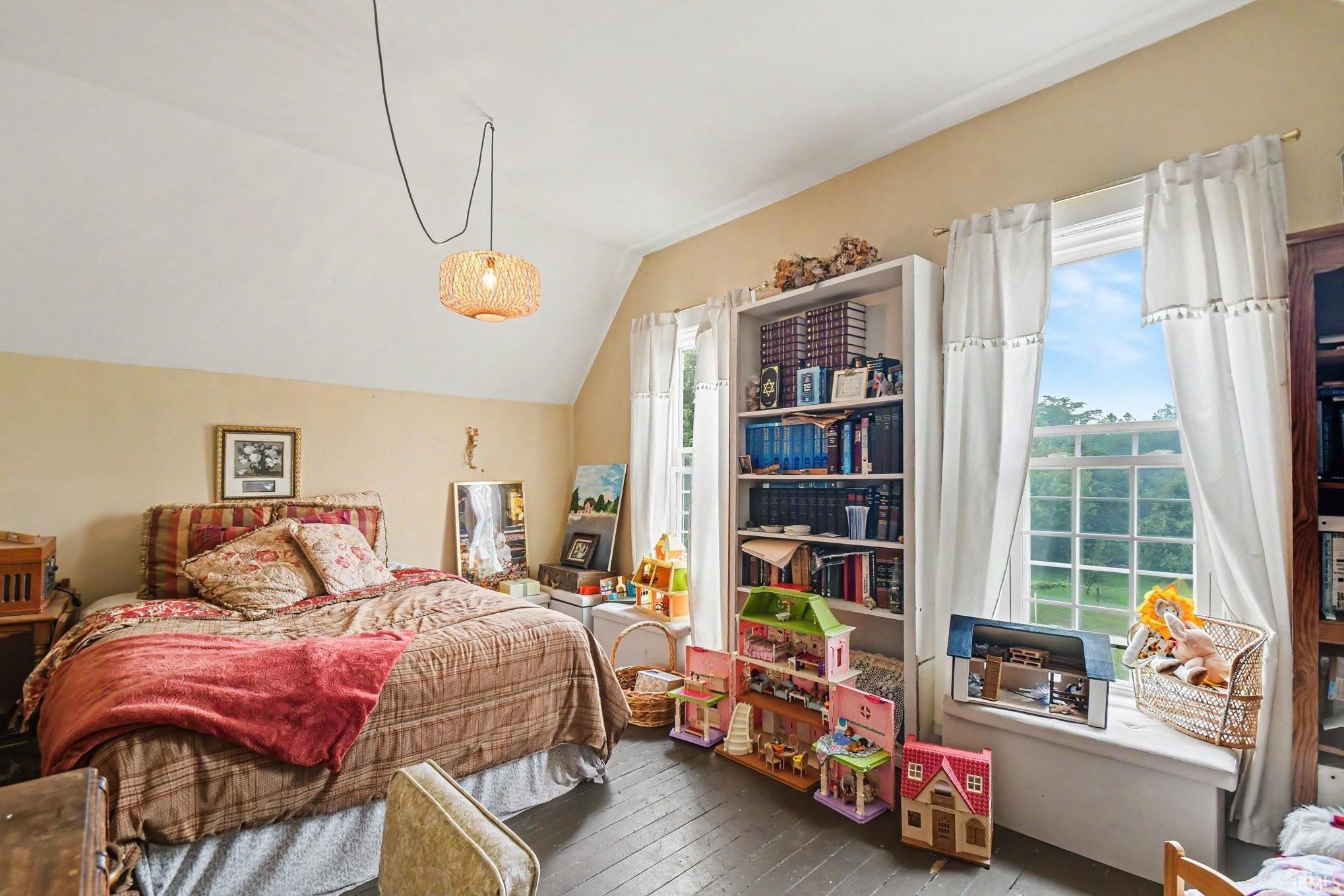 Room featuring wood-finish flooring, two large windows, built-in shelving, a window seat, and a woven pendant light fixture