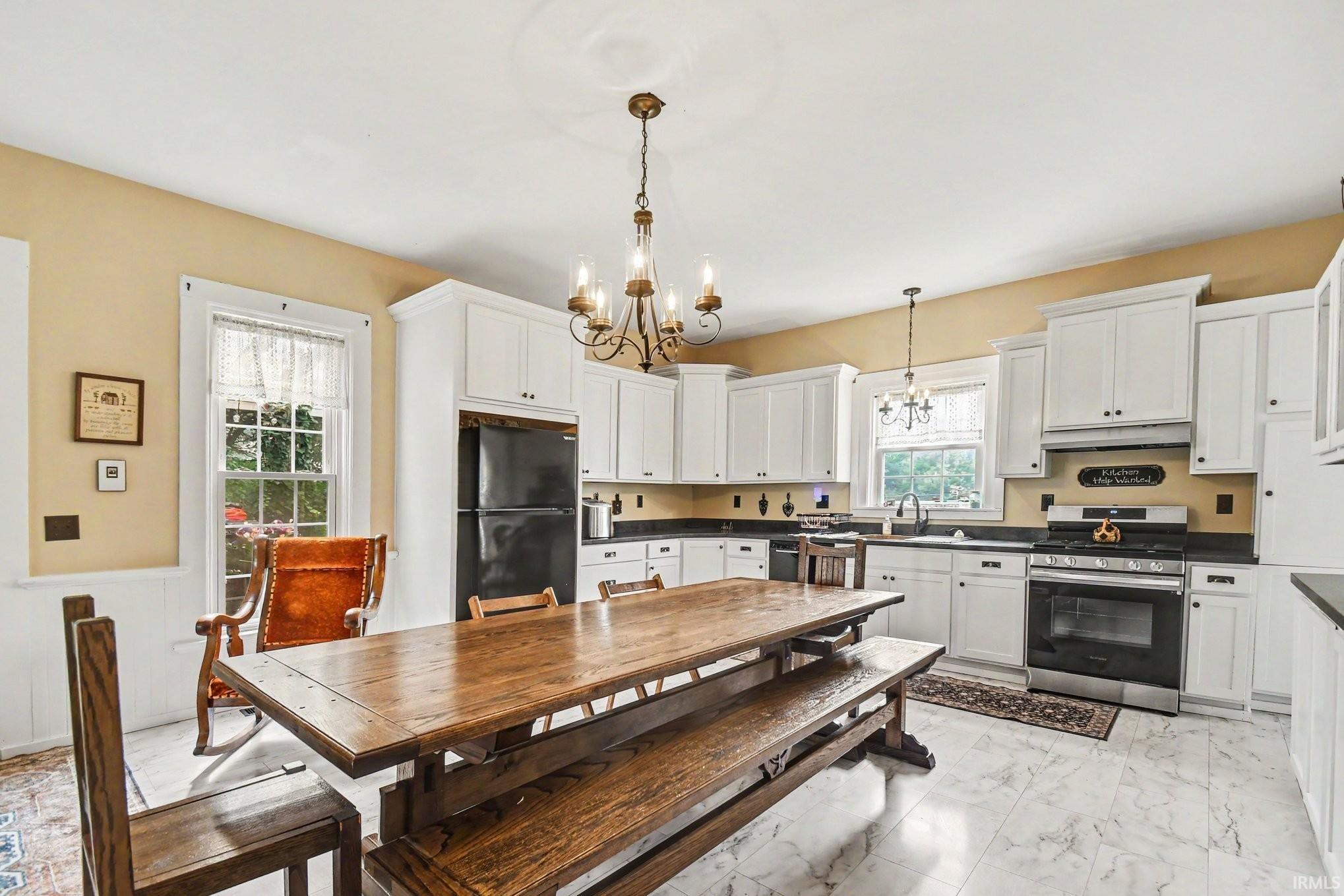Kitchen featuring white cabinetry with dark hardware, dark countertops, and stainless steel appliances