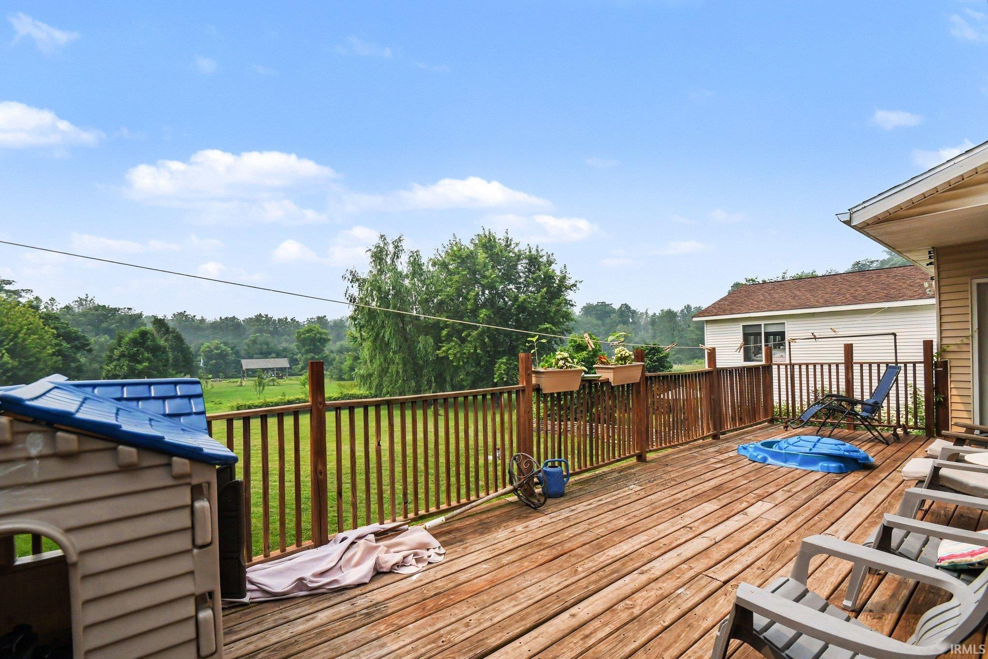Spacious outdoor deck featuring natural wood flooring and railing, with a direct walk-out from the residence