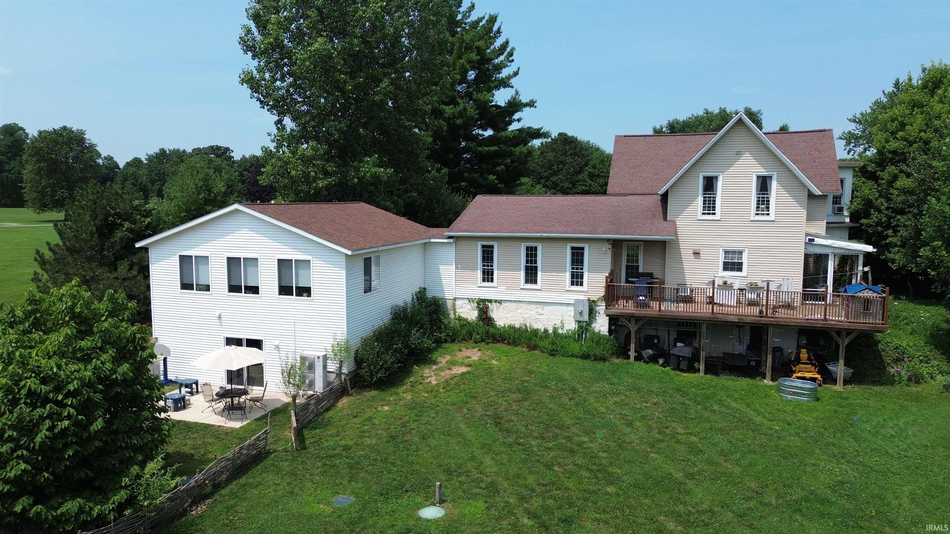 Two-story residence featuring white siding and light-colored siding sections, complemented by a brown shingle roof