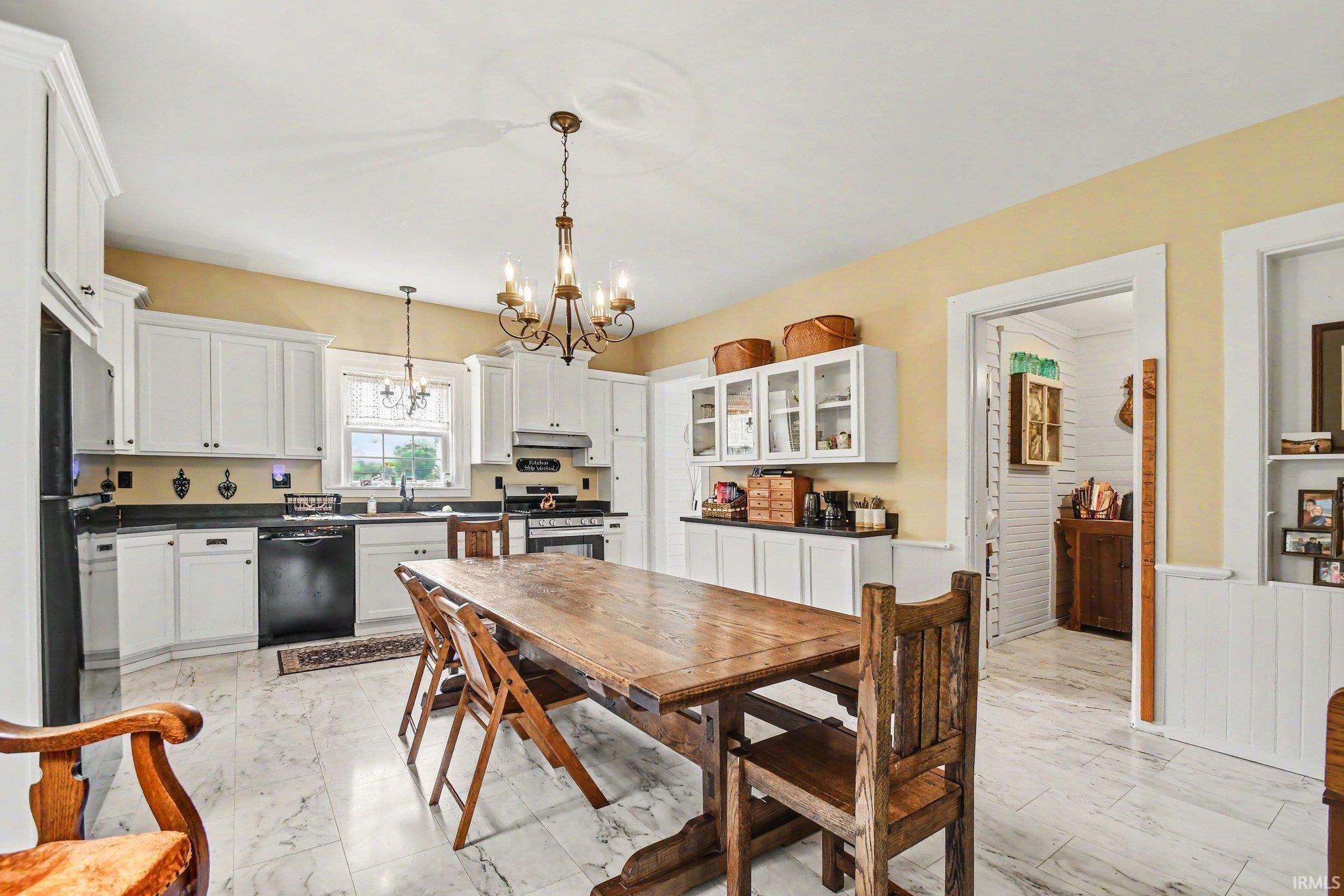 Spacious kitchen featuring white cabinetry, black appliances, dark countertops, and marble-look tile flooring
