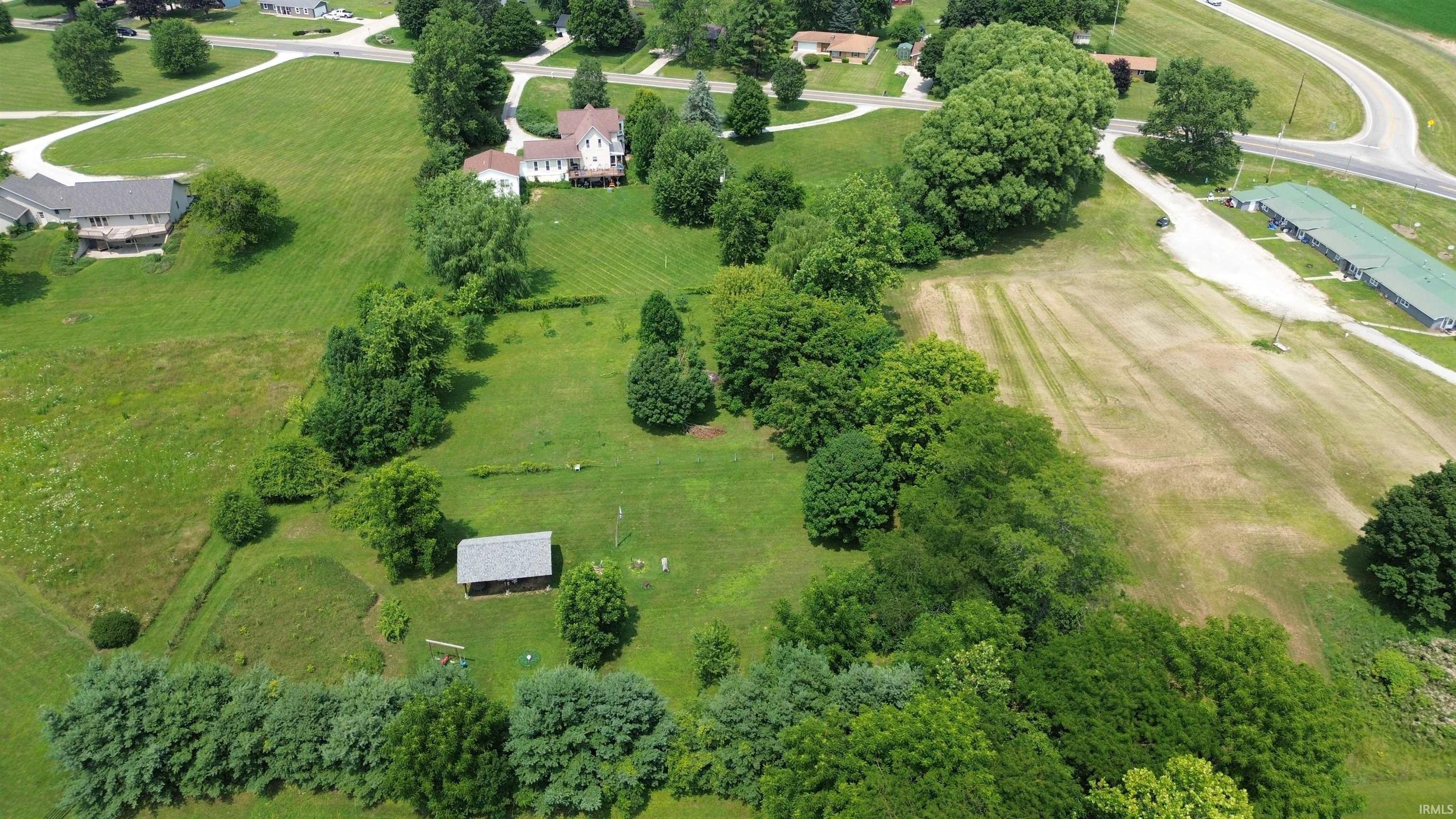 Expansive property featuring a two-story residence, a detached shed, abundant mature trees, and open green spaces