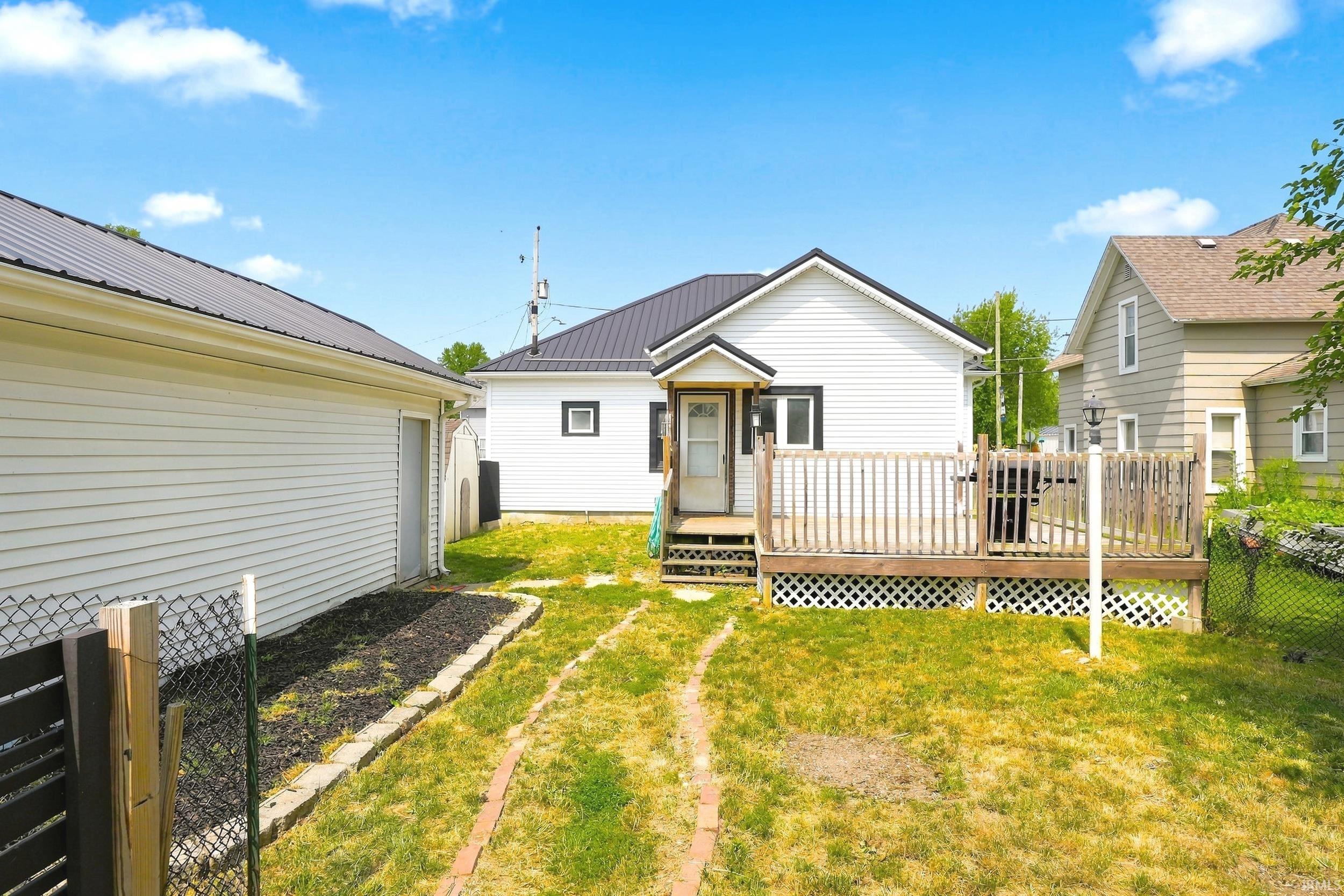 Rear exterior featuring white siding and a metal roof