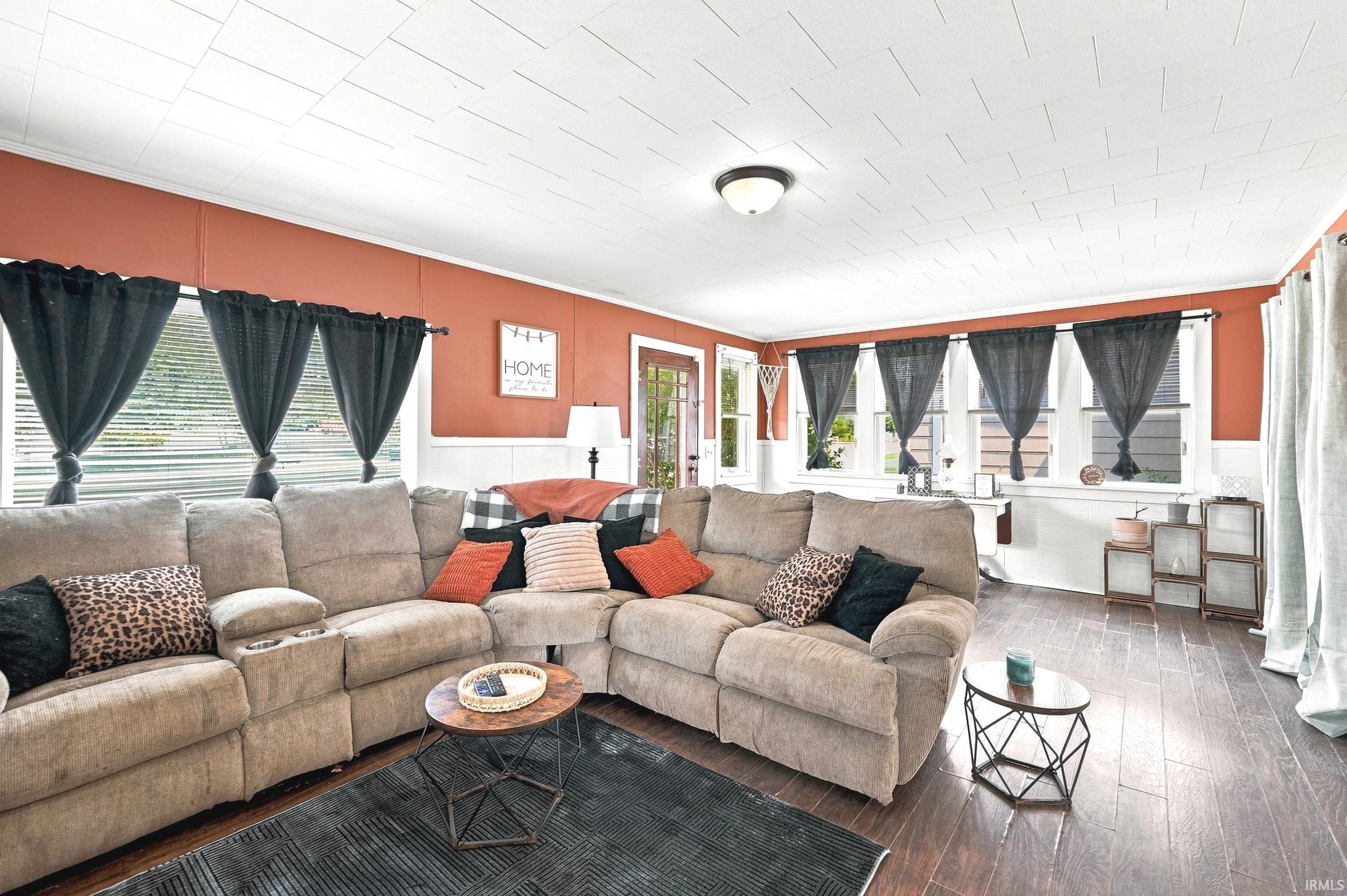 Spacious living area featuring wood-finish flooring, a white textured ceiling, and multiple windows with white trim
