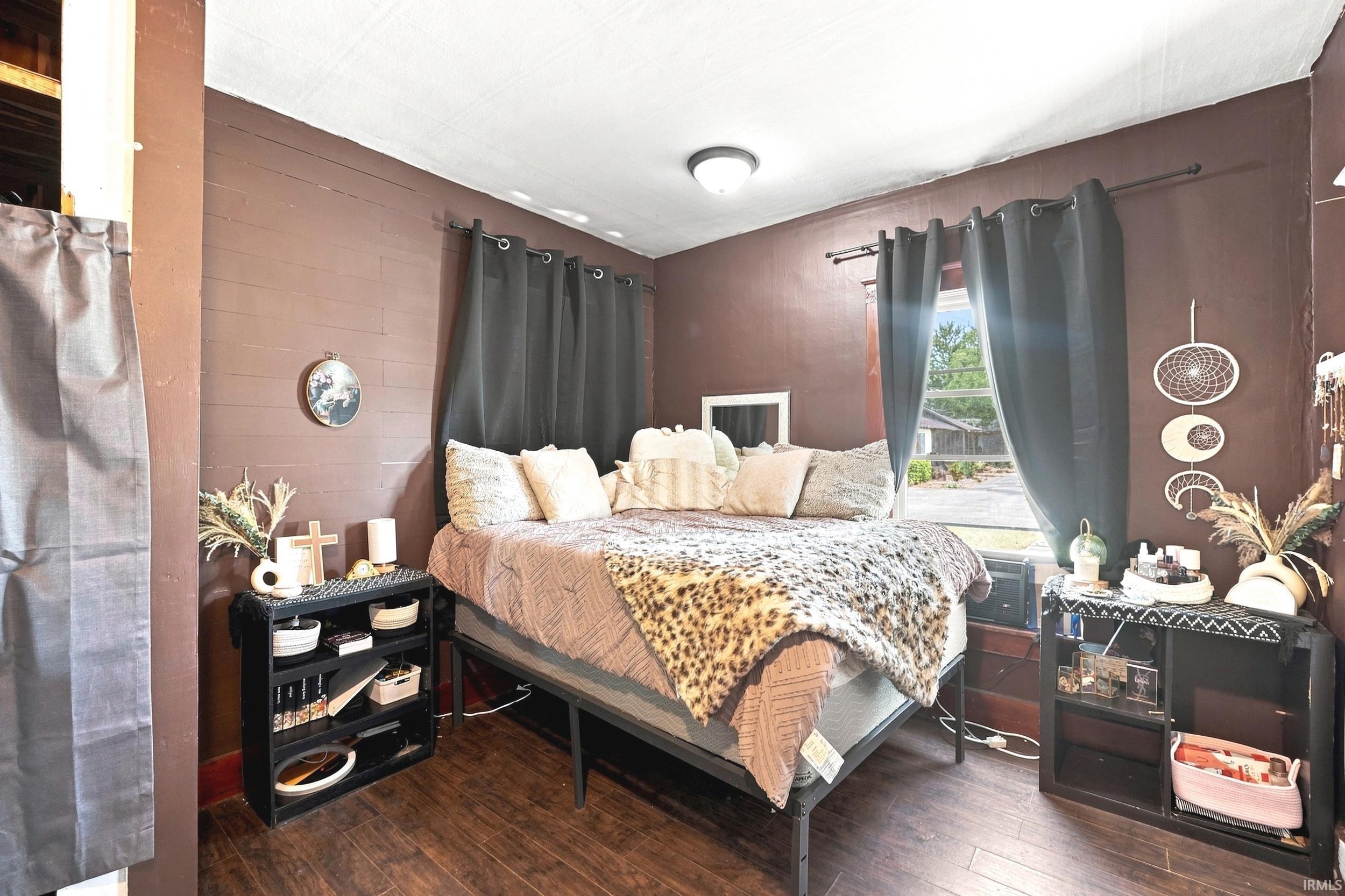 Bedroom featuring wood-finish flooring, a single window with curtain rod, and a flush-mount ceiling light fixture
