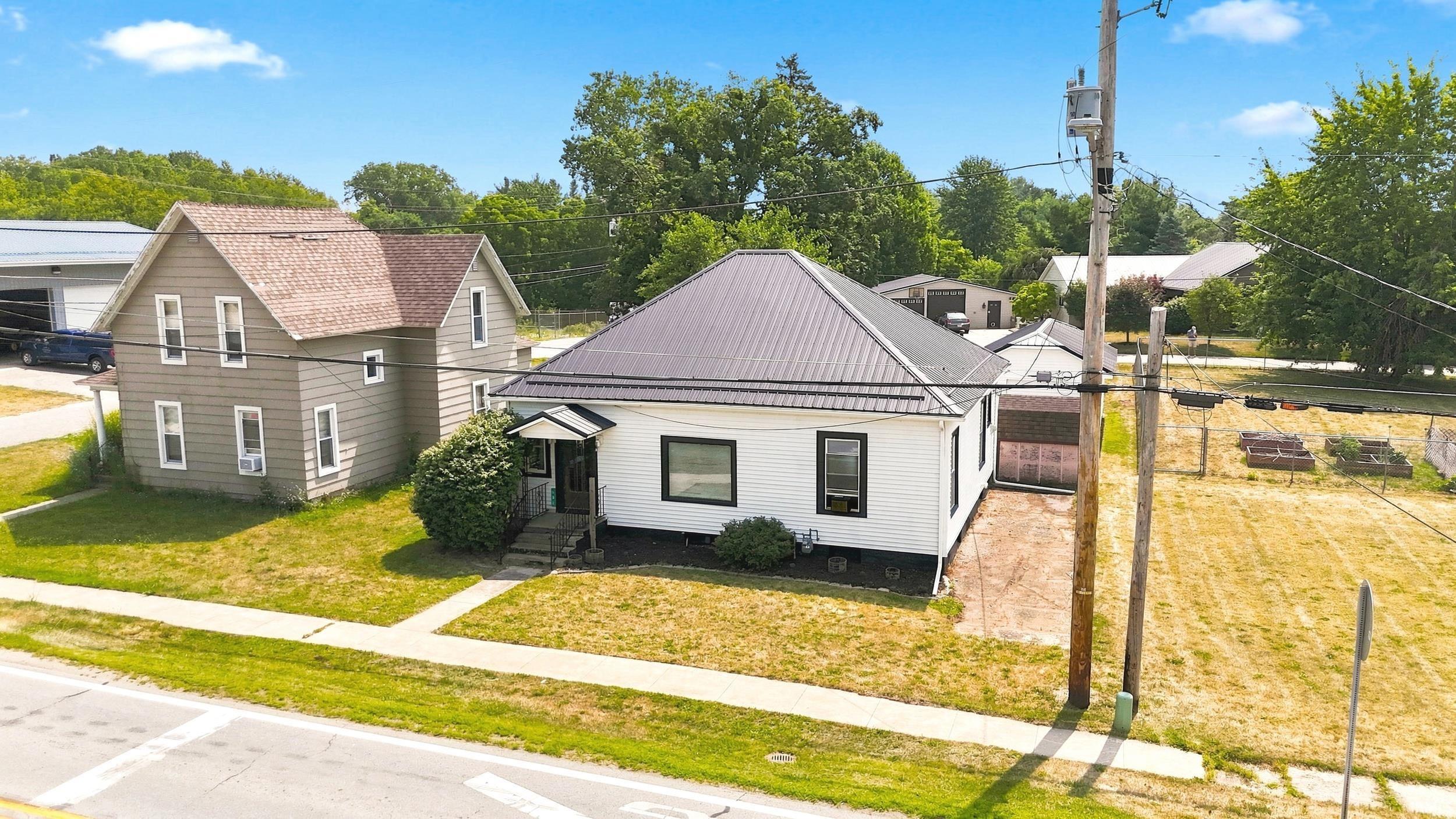 Single-story residence featuring white siding and a black metal roof