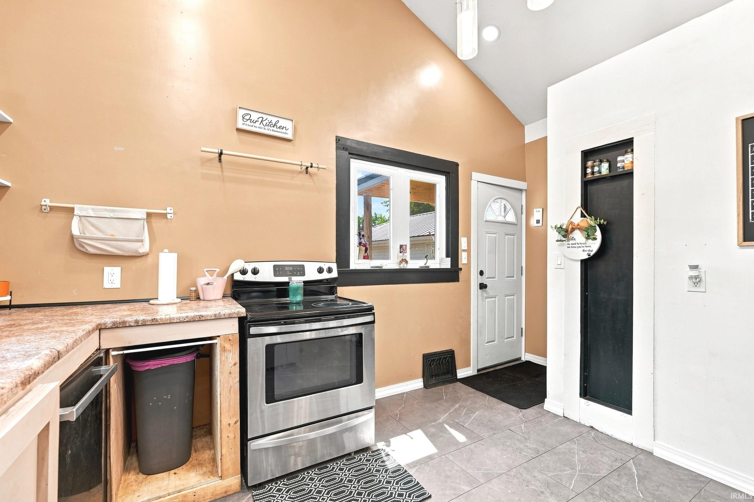 Kitchen area featuring stainless steel range, light-toned countertop, and gray tile flooring