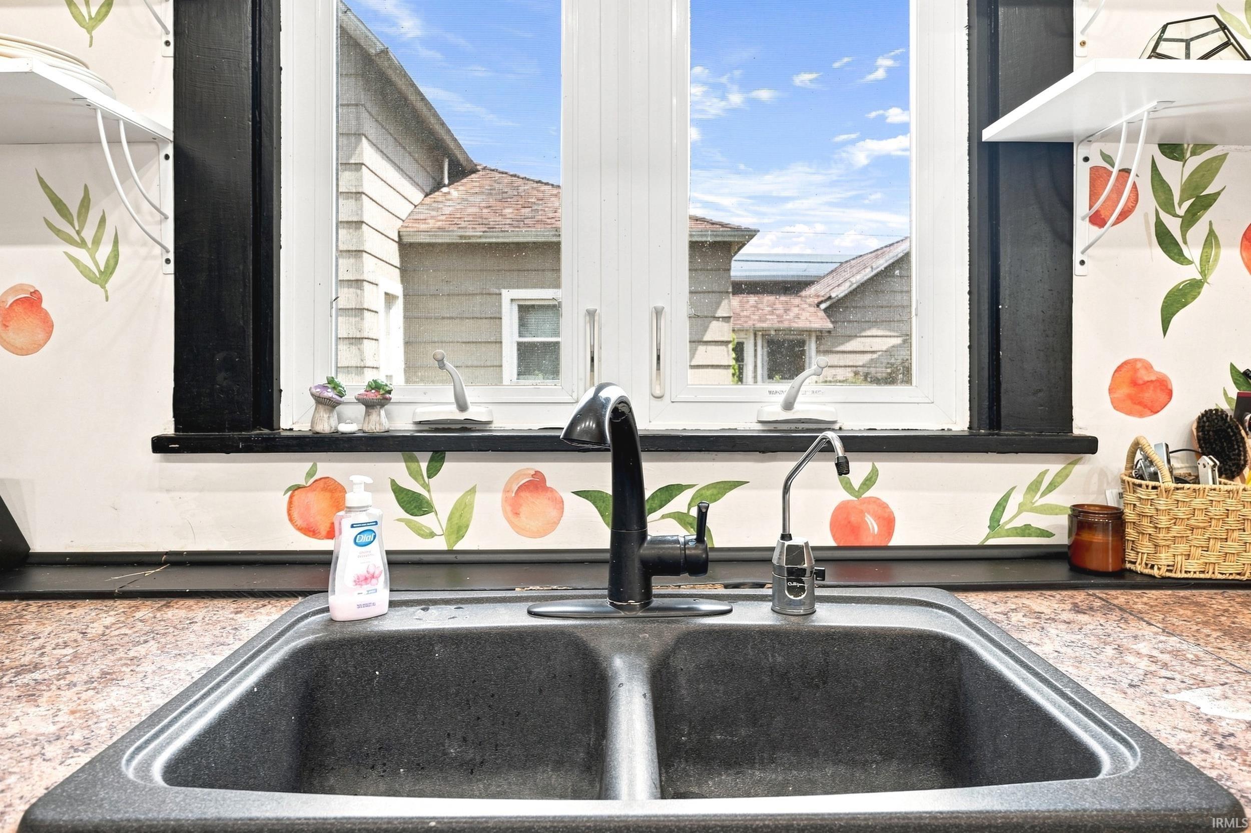Dual basin sink with a matte black faucet and a separate water filtration tap set within a speckled countertop