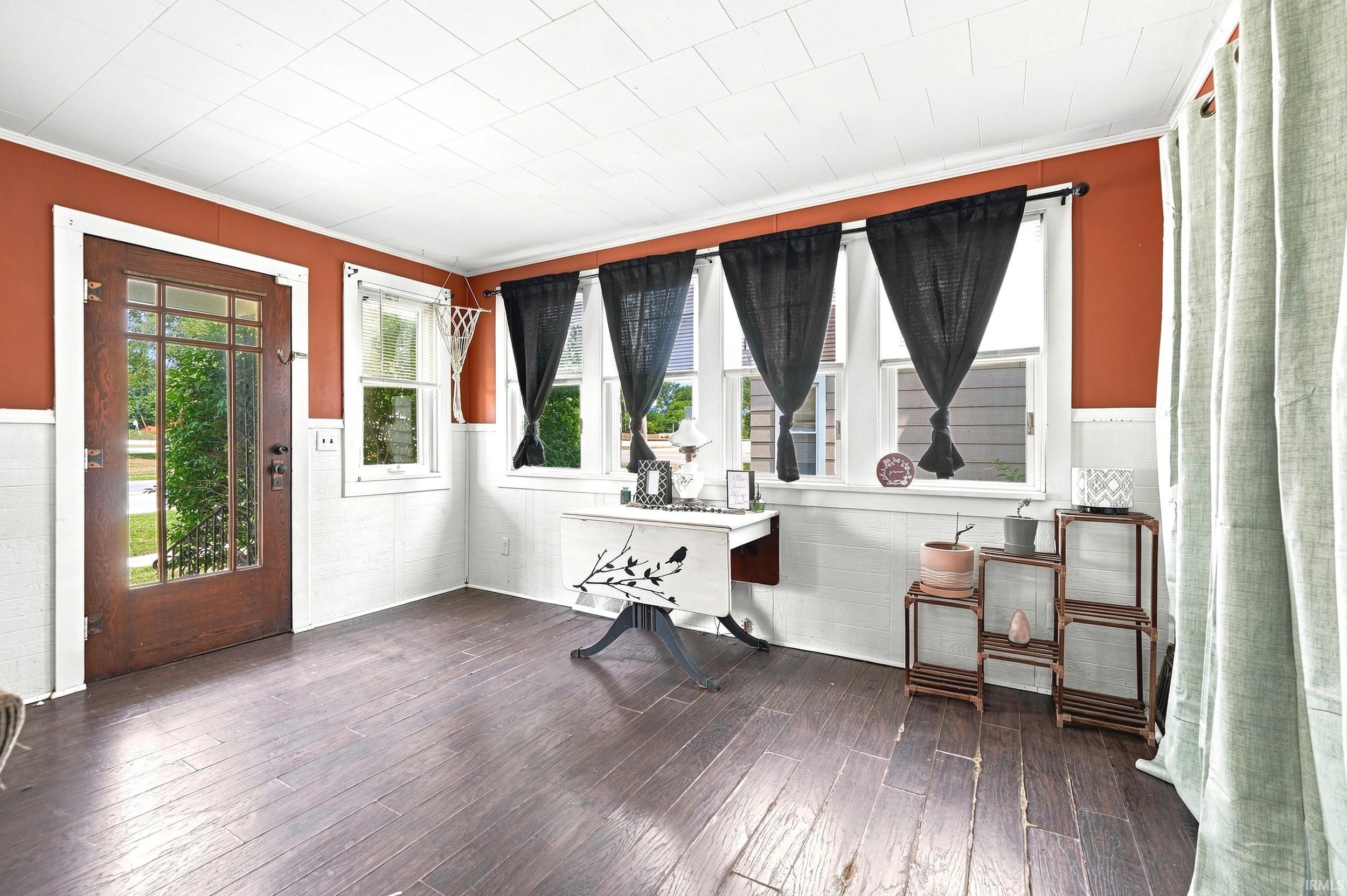Entry room featuring a full-light wood-finish door, multiple windows, board and batten wainscoting, and wood-finish flooring