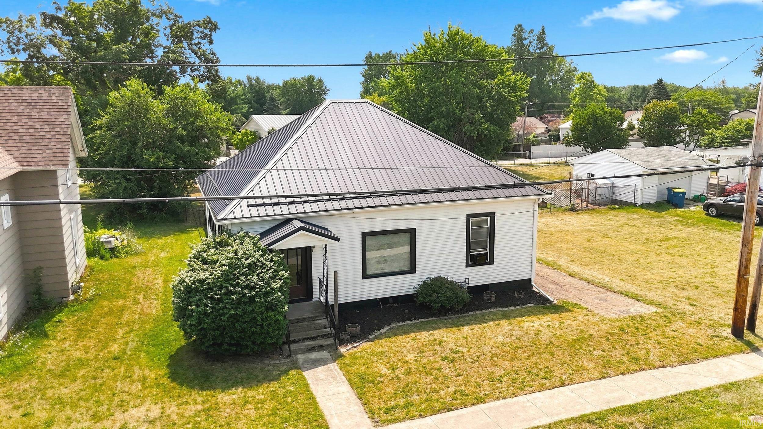 White siding exterior with black trim windows, a dark metal roof, and a covered entry