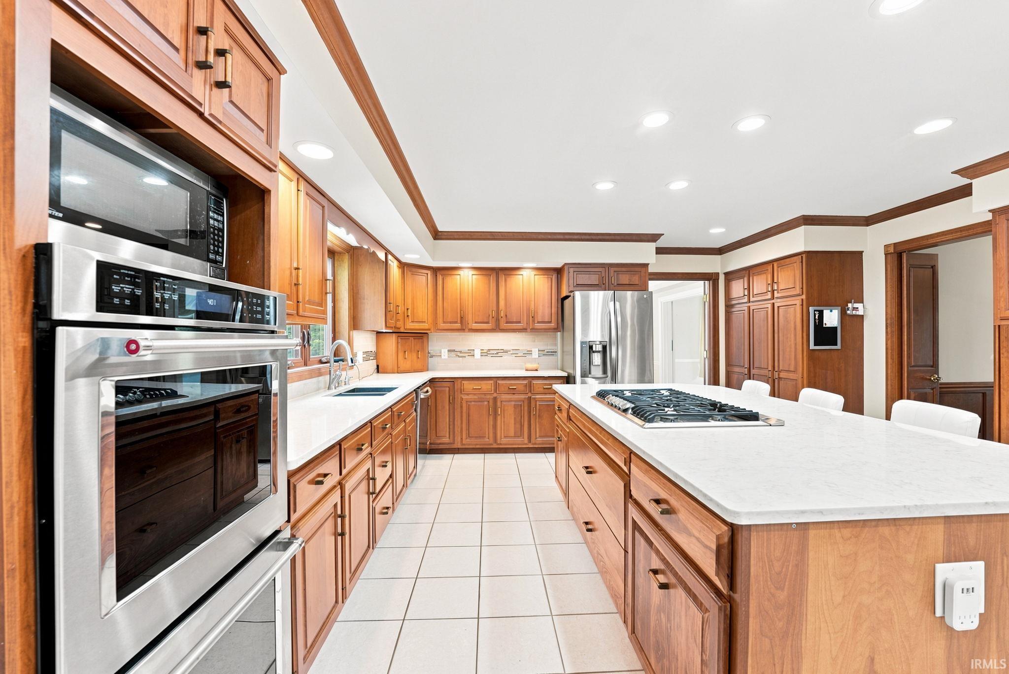 Spacious kitchen with extensive wood cabinetry, white tile flooring, and recessed lighting