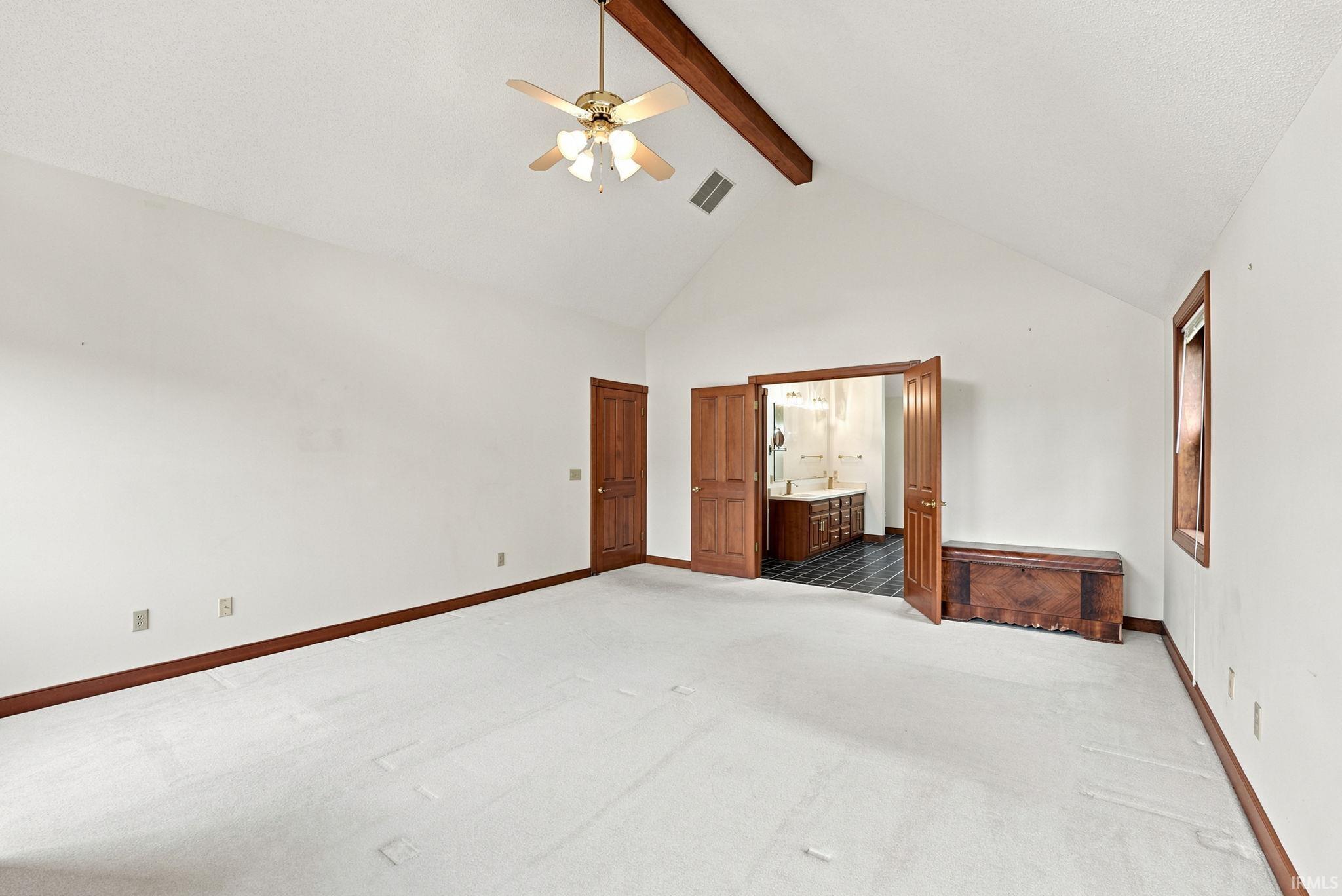 Spacious interior room with vaulted ceilings and a ceiling fan