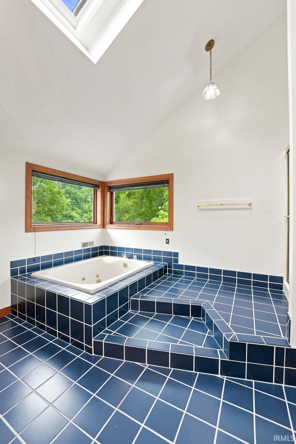Soaking tub with blue tile surround and steps