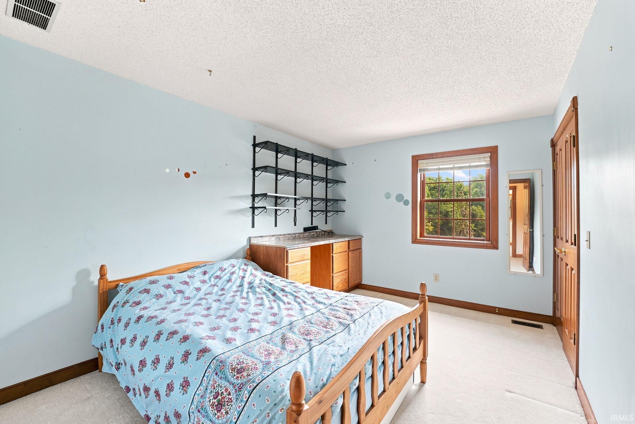 Carpeted room featuring a built-in desk with wood cabinetry, a window with wood trim, and a paneled wood door