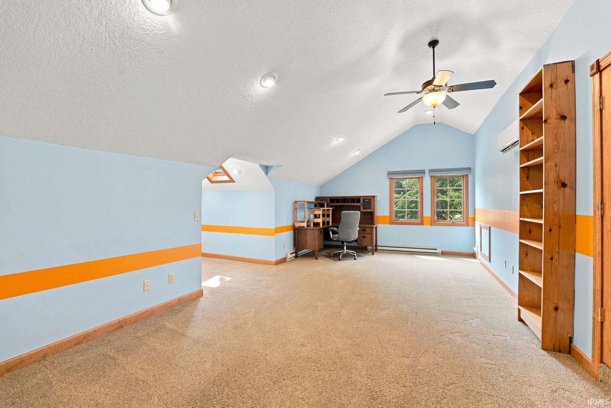 Spacious room featuring vaulted ceilings, recessed lighting, and a ceiling fan