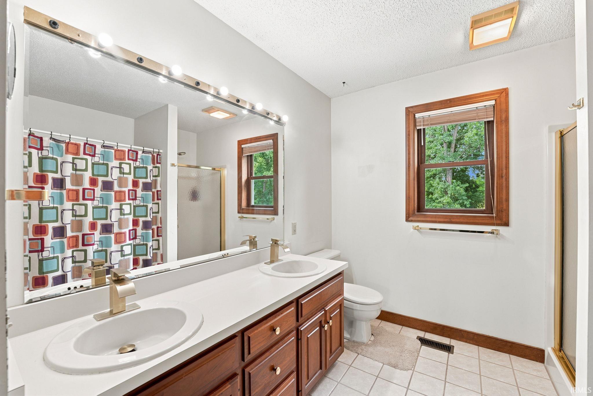 Dual vanity with white countertop, recessed sinks, and brass fixtures