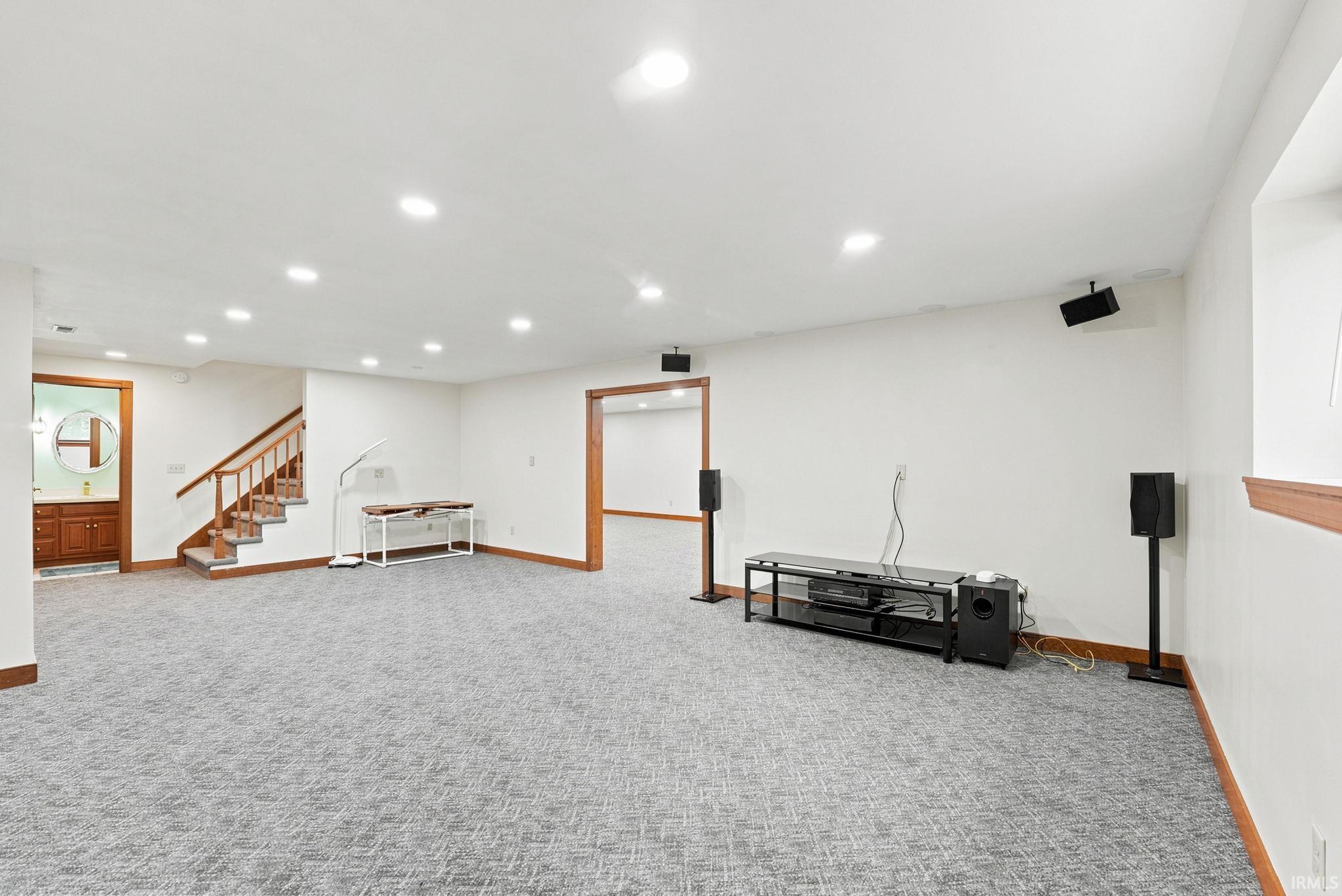 Spacious lower level featuring recessed lighting, light gray patterned carpeting, white walls, and wood trim throughout