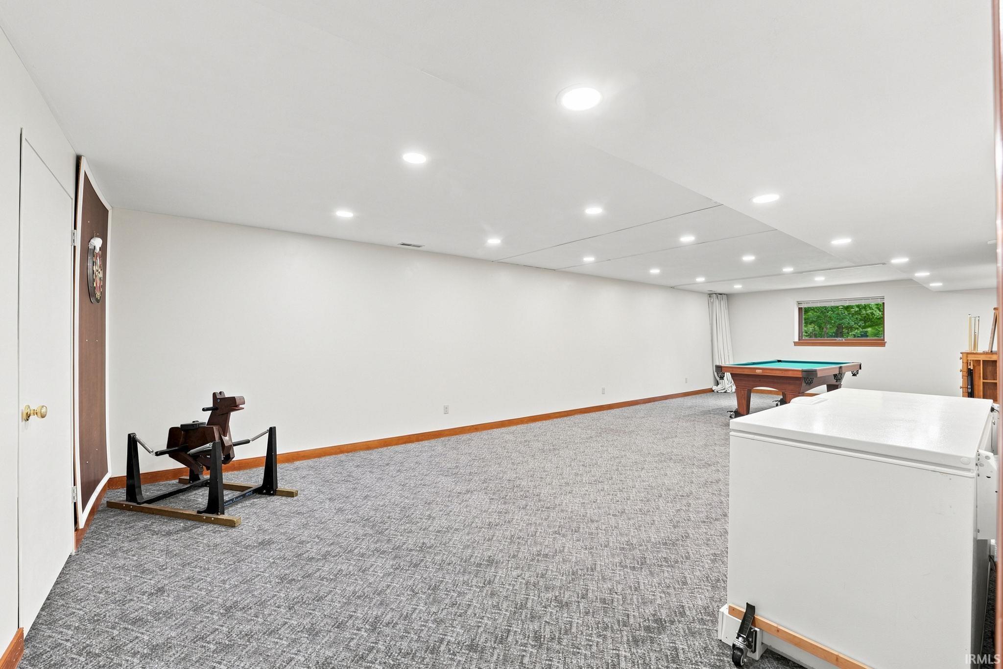 Spacious finished basement with recessed lighting, patterned gray carpet, white walls, and a visible window