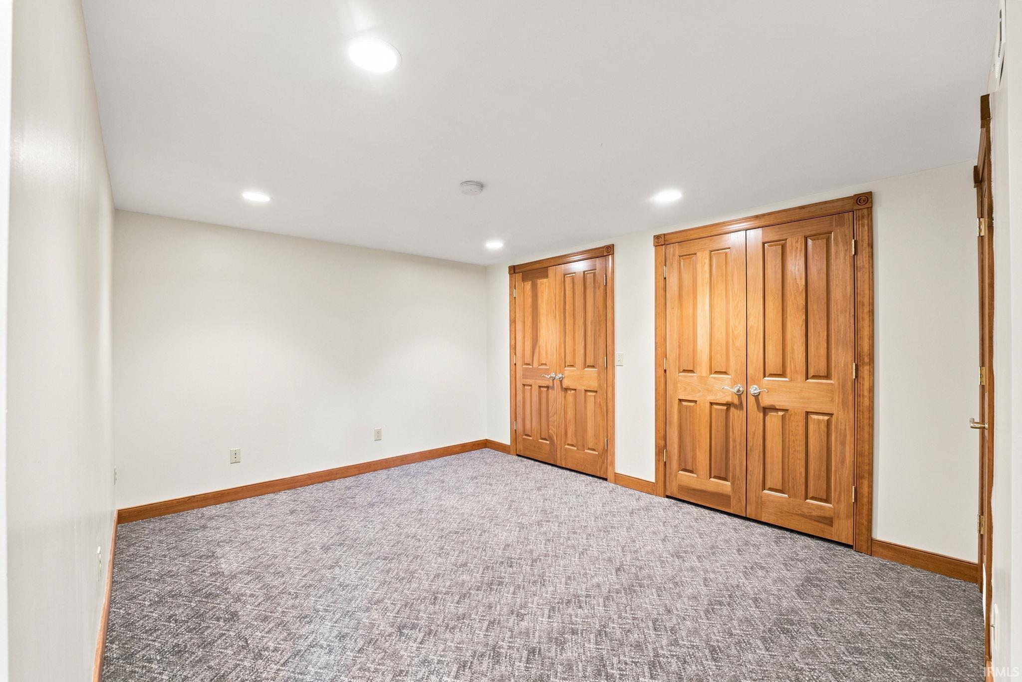 Spacious interior room featuring two sets of wood-paneled double doors, neutral-toned walls, and recessed ceiling lighting