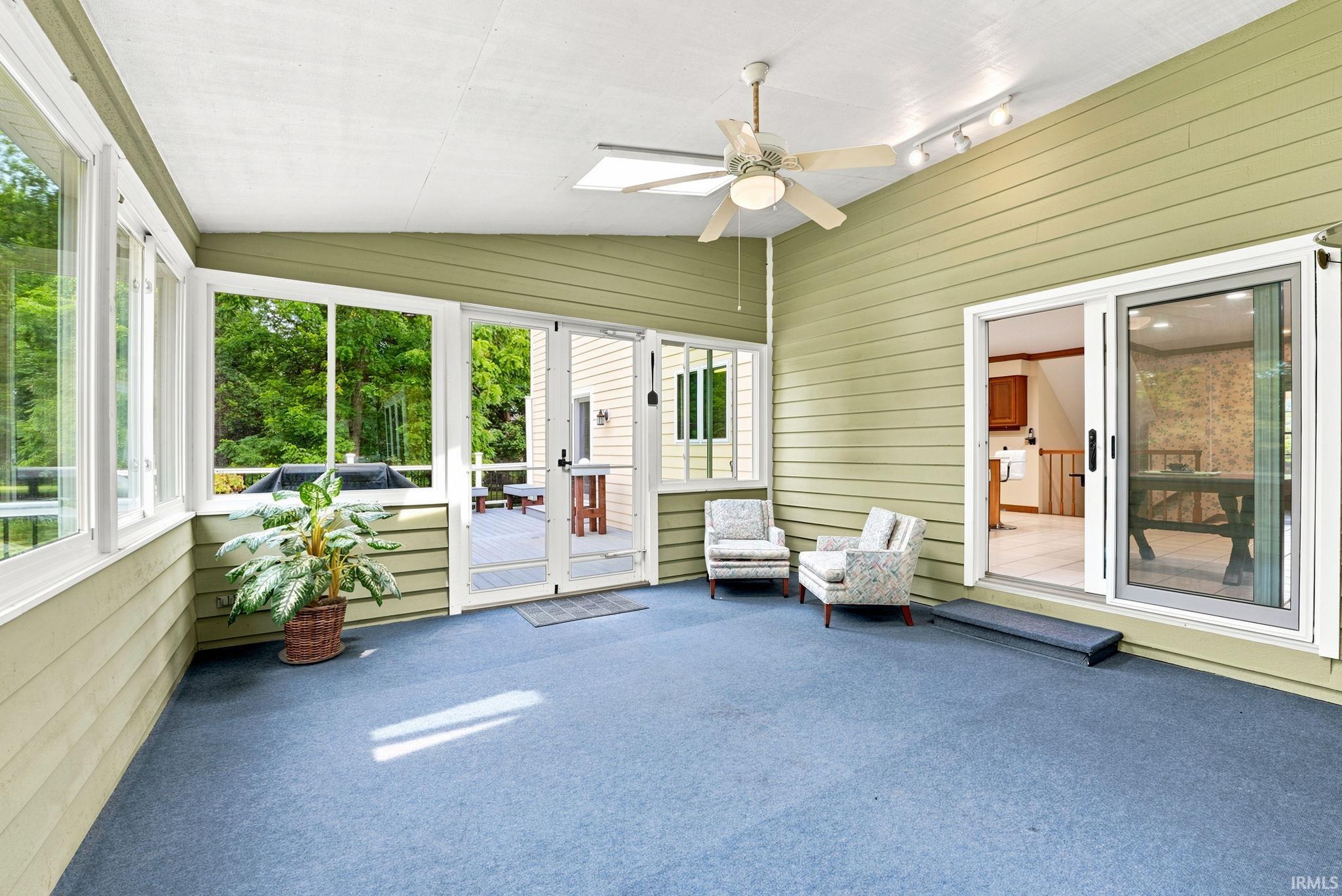 Enclosed sunroom featuring blue carpeting, a white ceiling with a ceiling fan, and track lighting