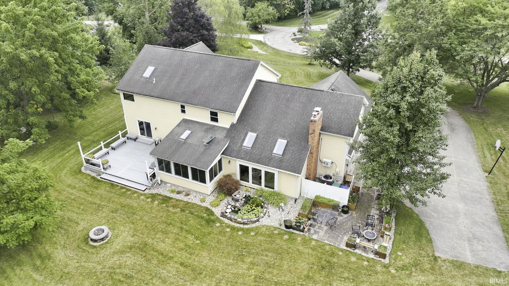 Expansive rear exterior featuring a multi-level deck, sunroom, and a paved patio area