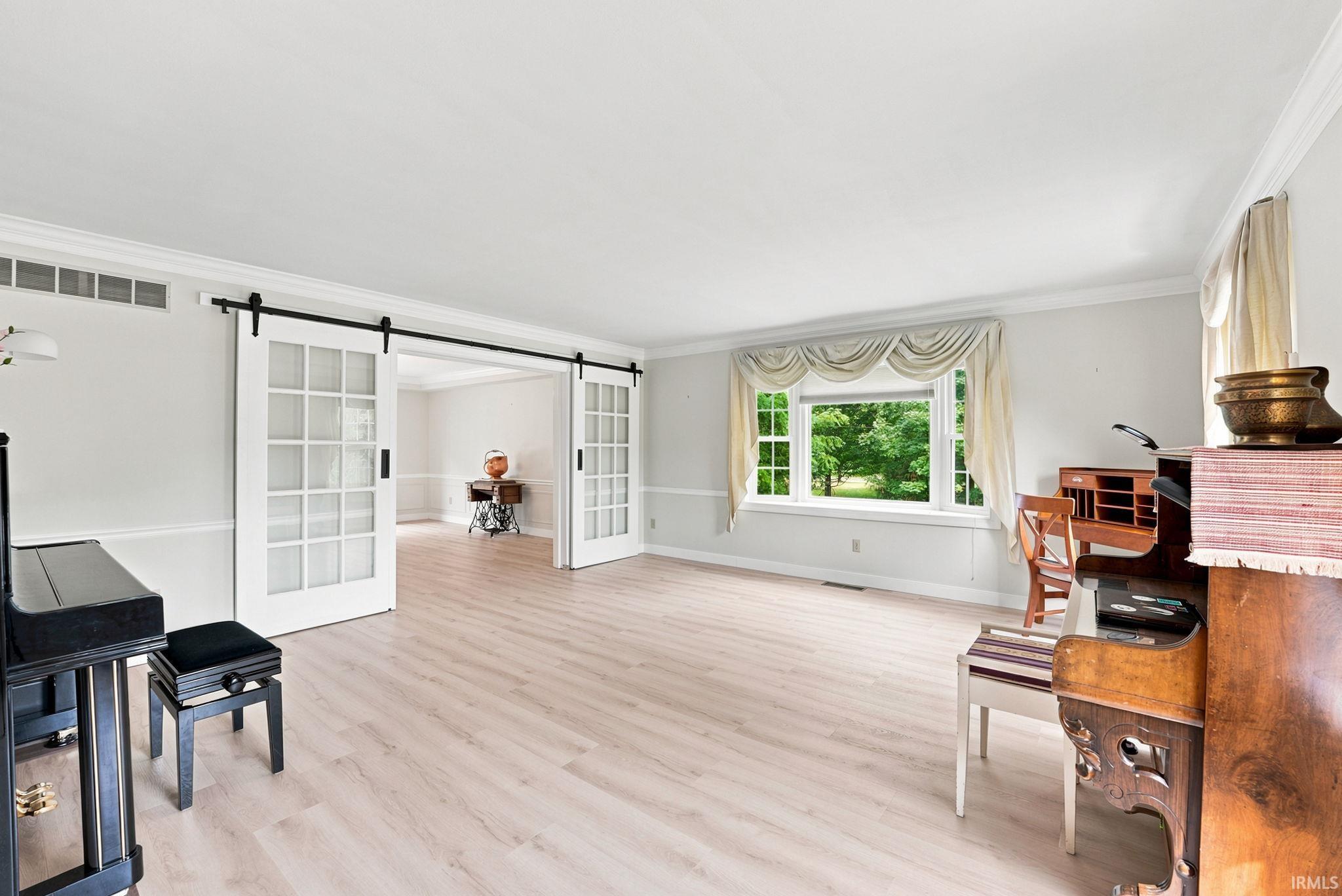 Bright room featuring light wood-finish flooring and a wide window with a wooded backdrop