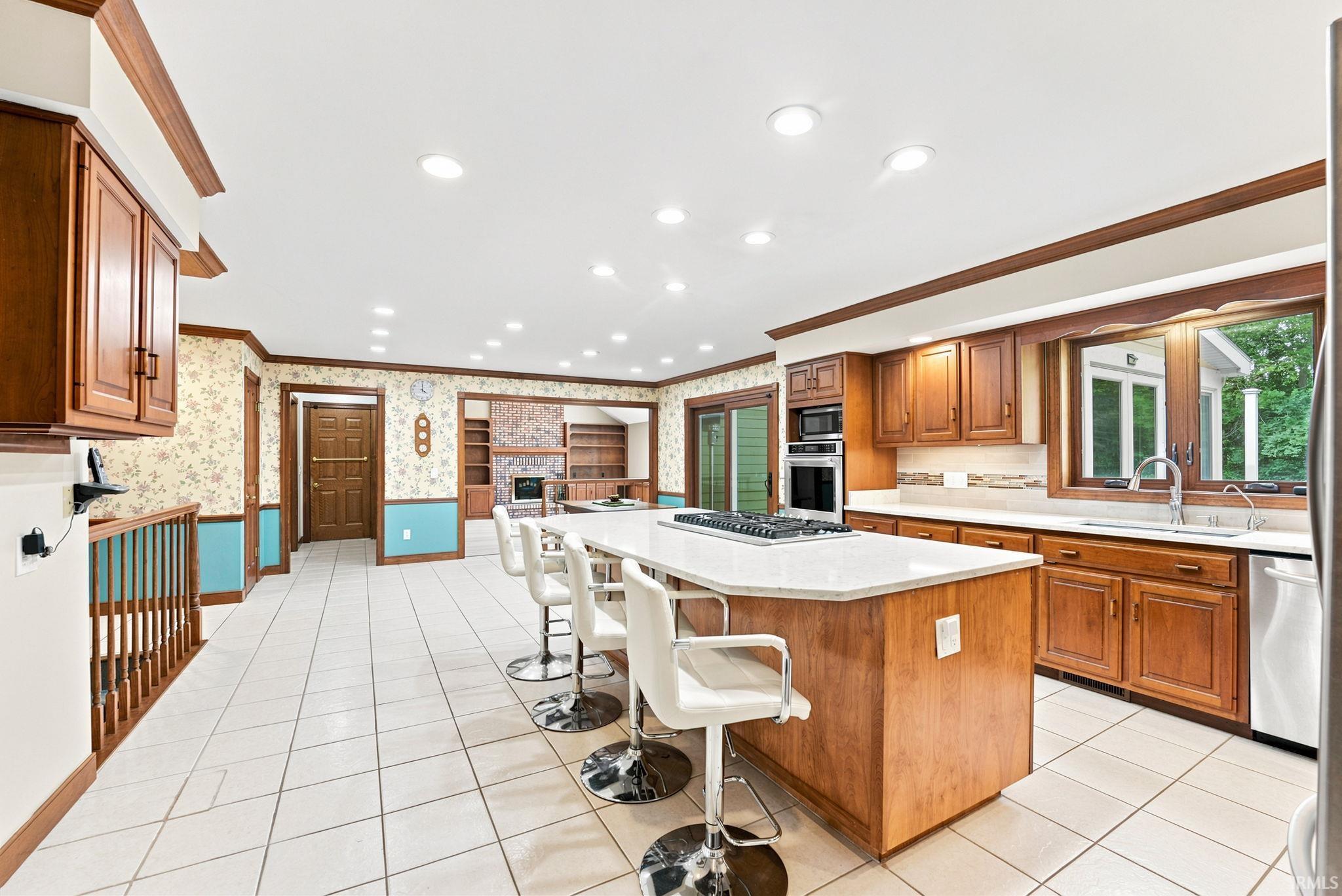 Spacious kitchen featuring a large central island with a built-in gas range, white countertop, and tiled flooring