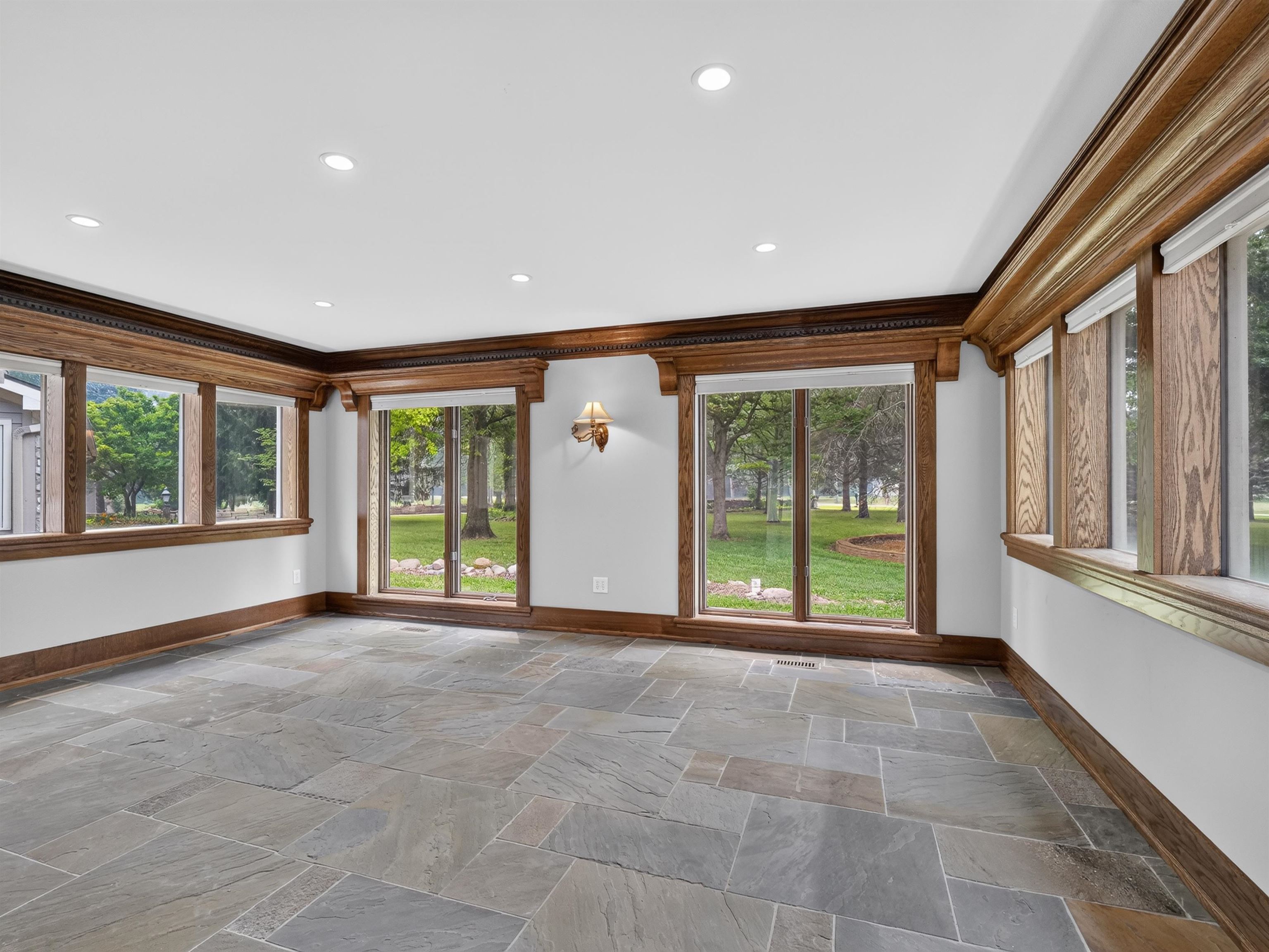 Spacious room featuring extensive custom wood trim, slate tile flooring, recessed lighting, and a wall sconce