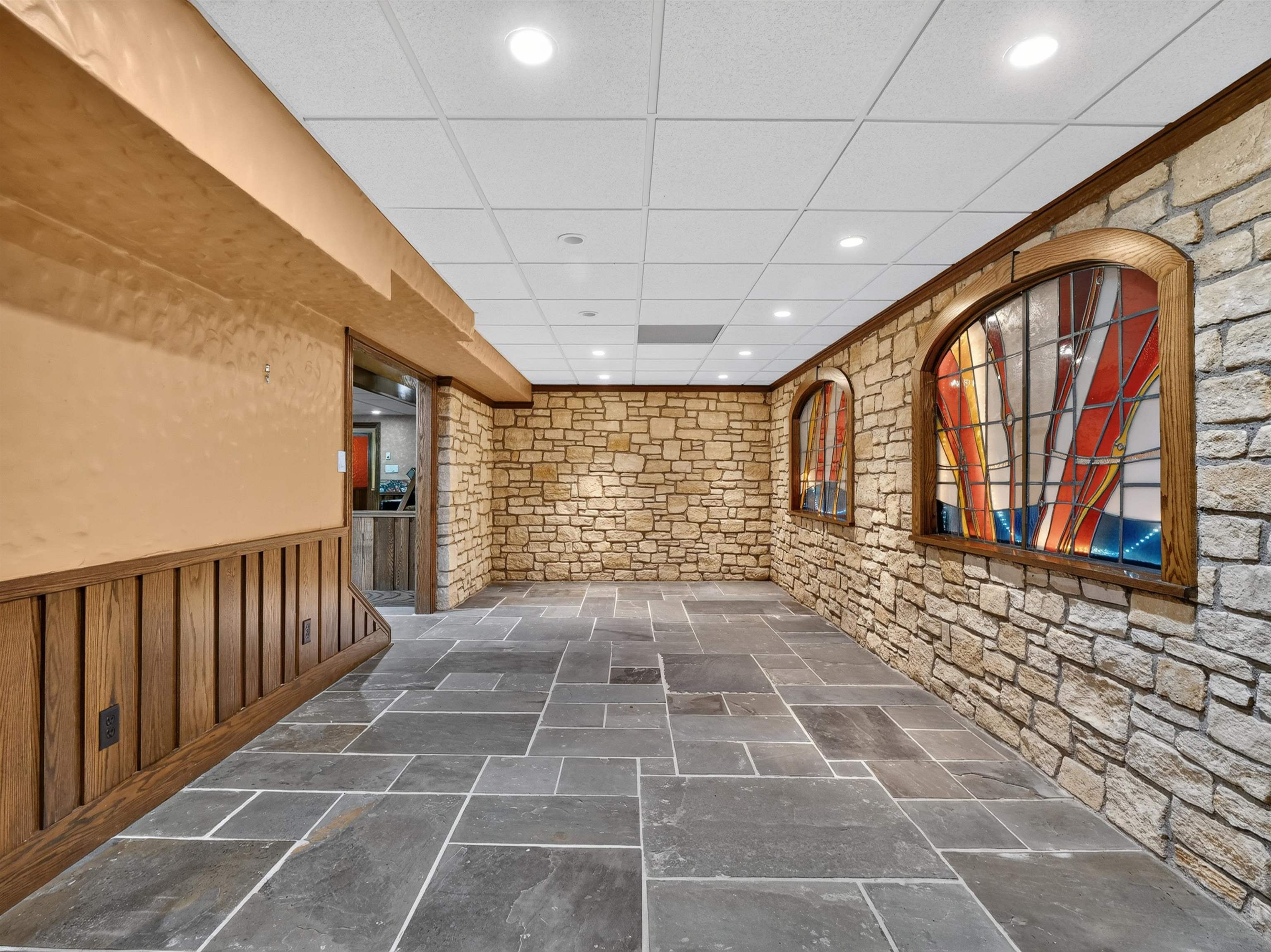 Stone accent walls featuring arched wood-framed stained glass windows