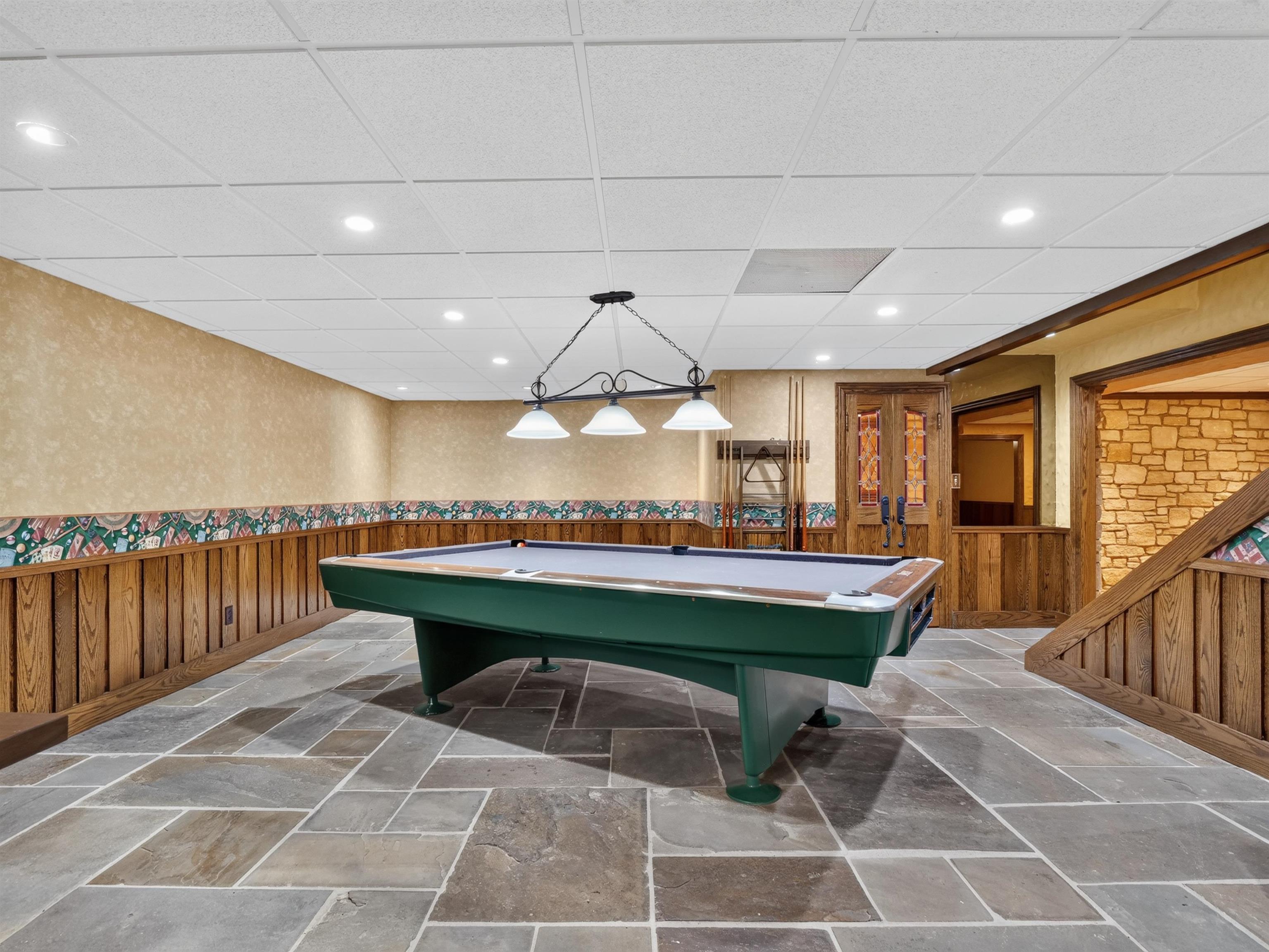 Spacious room featuring flagstone flooring, wood paneling, and a drop ceiling with recessed lighting