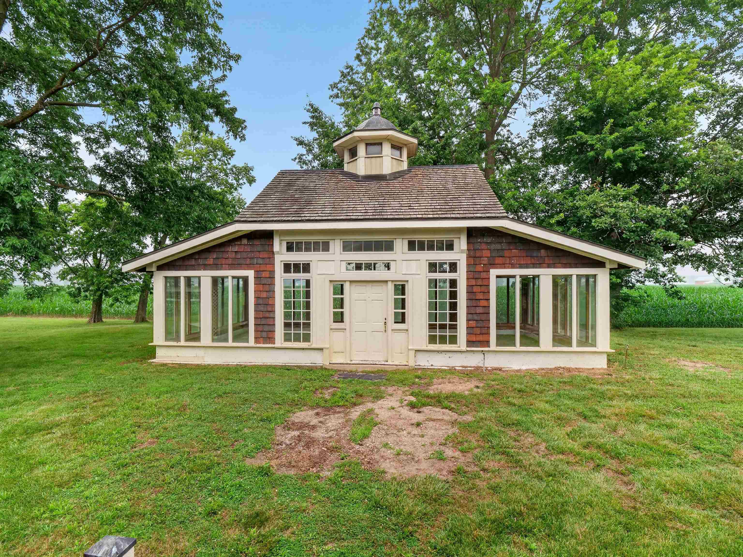 Detached structure featuring a cupola, shingle siding, a gambrel roof, and multiple large windows with white trim