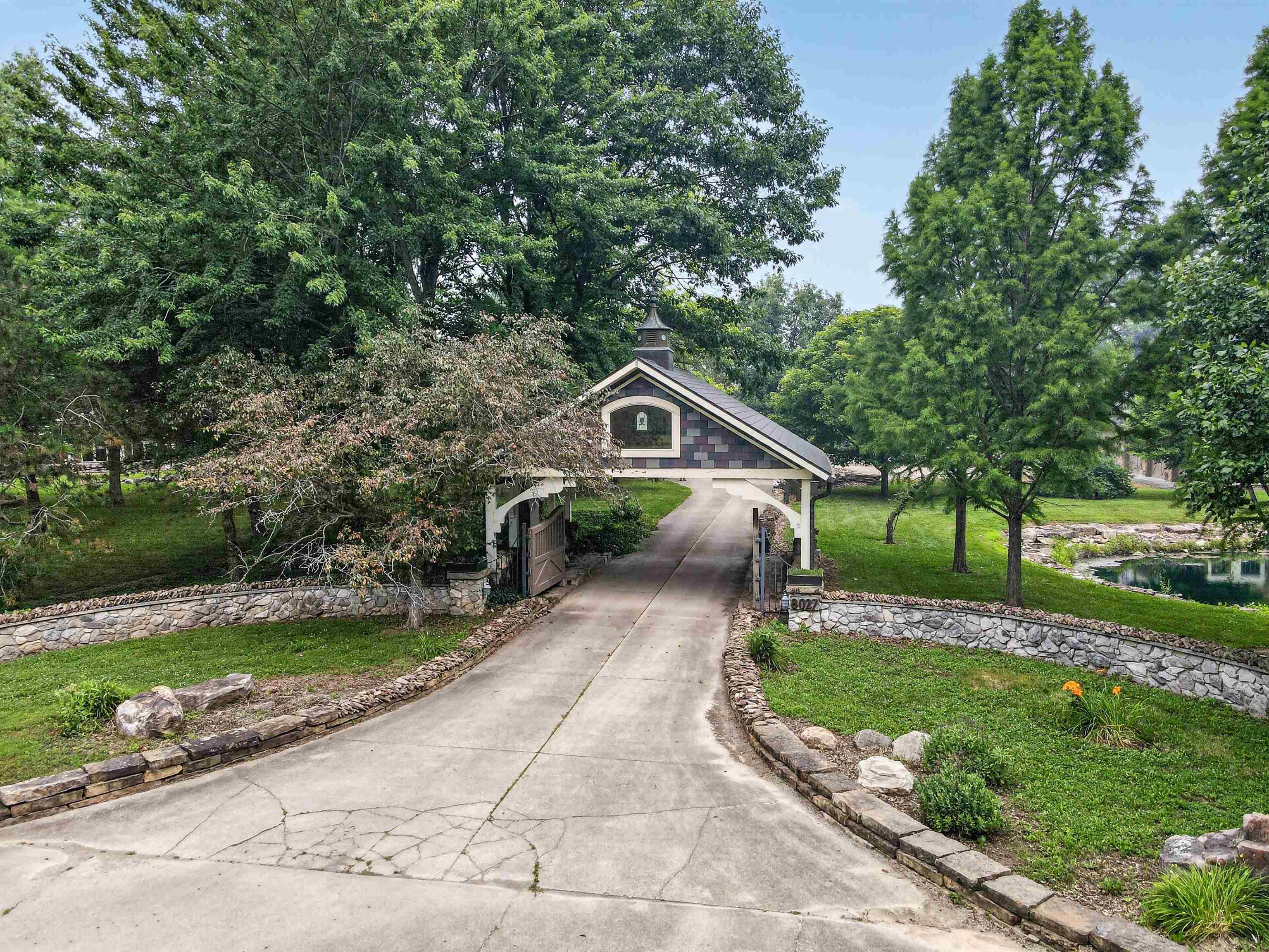 Gated entry with a stone wall surround and mature trees