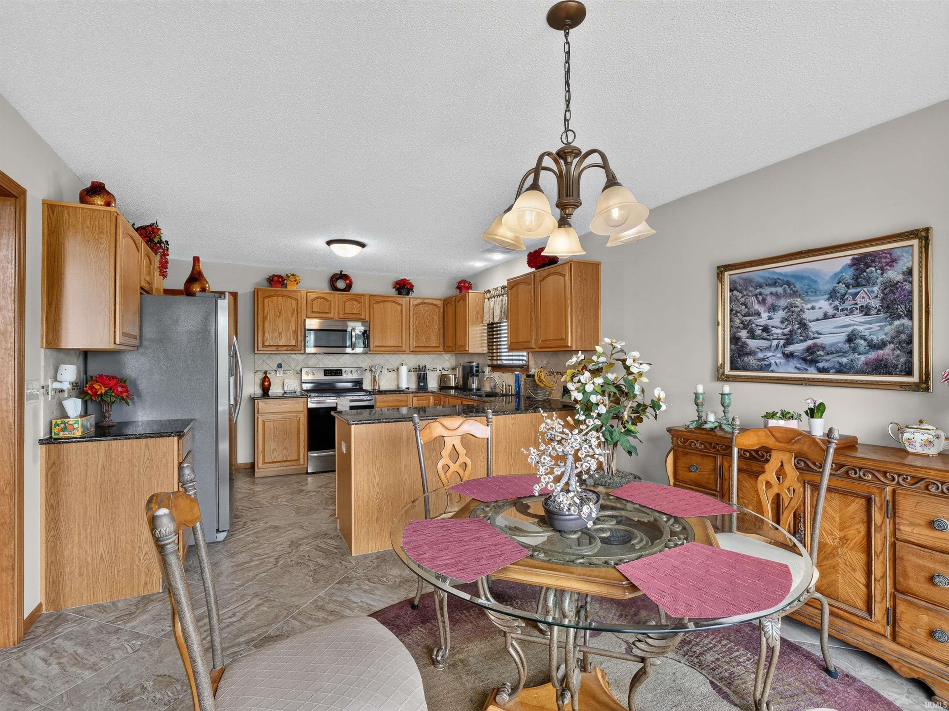 Dining area with a glass-top table, chandelier lighting, and tile flooring