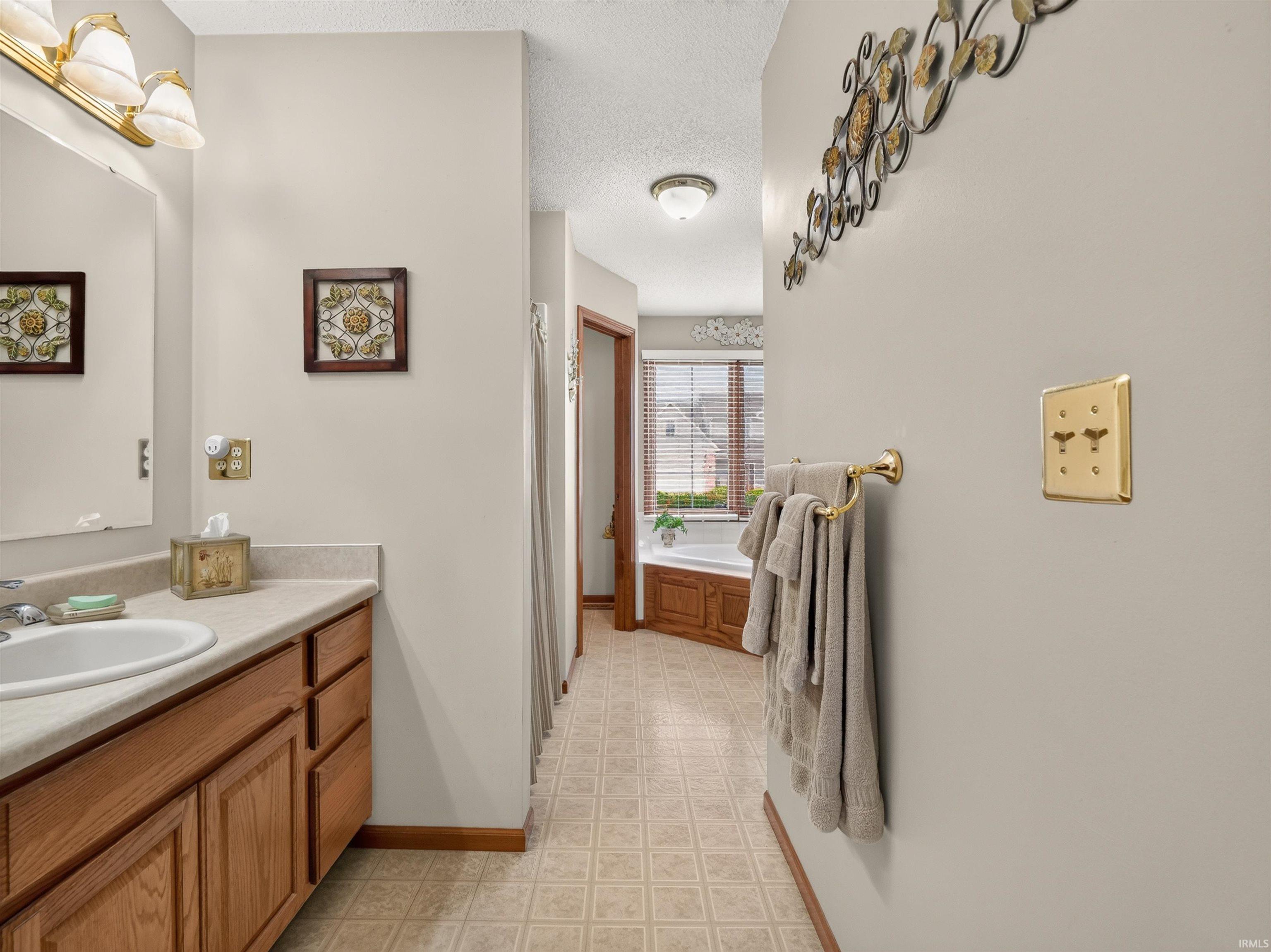Bathroom vanity featuring a light-colored countertop, an undermount sink, and wood-finish cabinetry