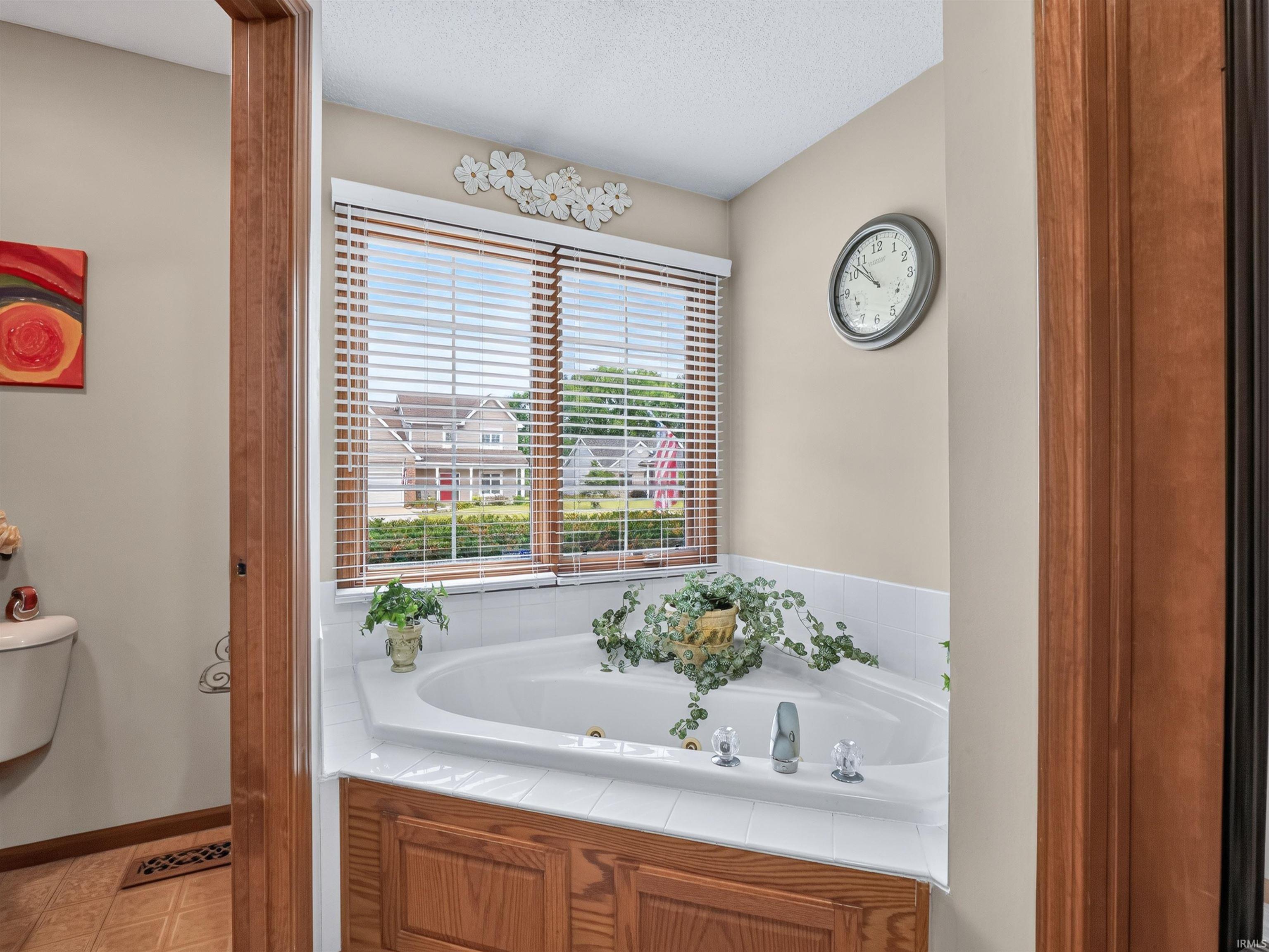 Corner jetted tub set within a white tile surround